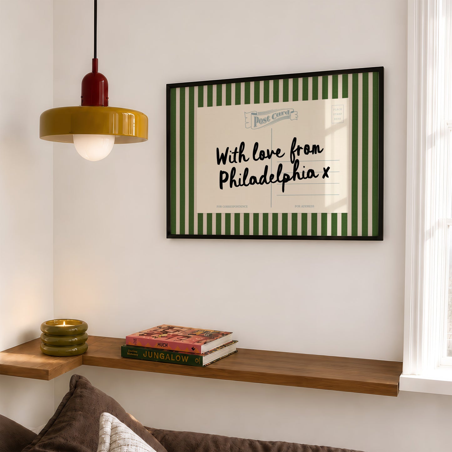 a cozy corner of a room with a wooden shelf, a lamp, and a framed postcard with a handwritten message.
