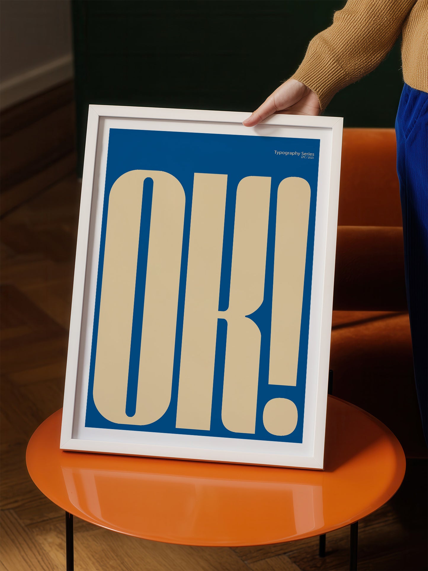 a person holding up a framed poster with a large, bold, and stylized "OK!" text on it.