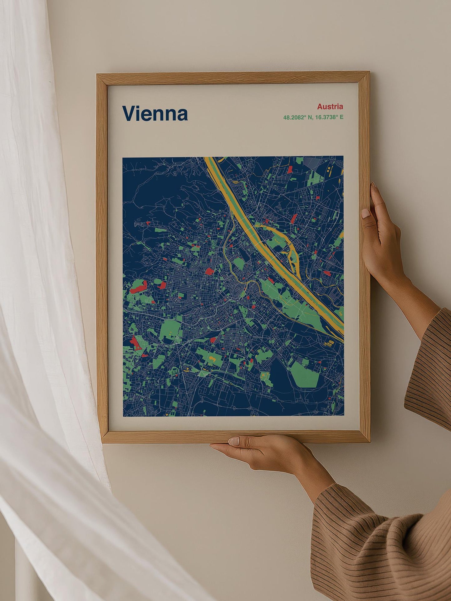 A person is holding a framed map of Vienna, Austria, which is a colorful and detailed representation of the city.