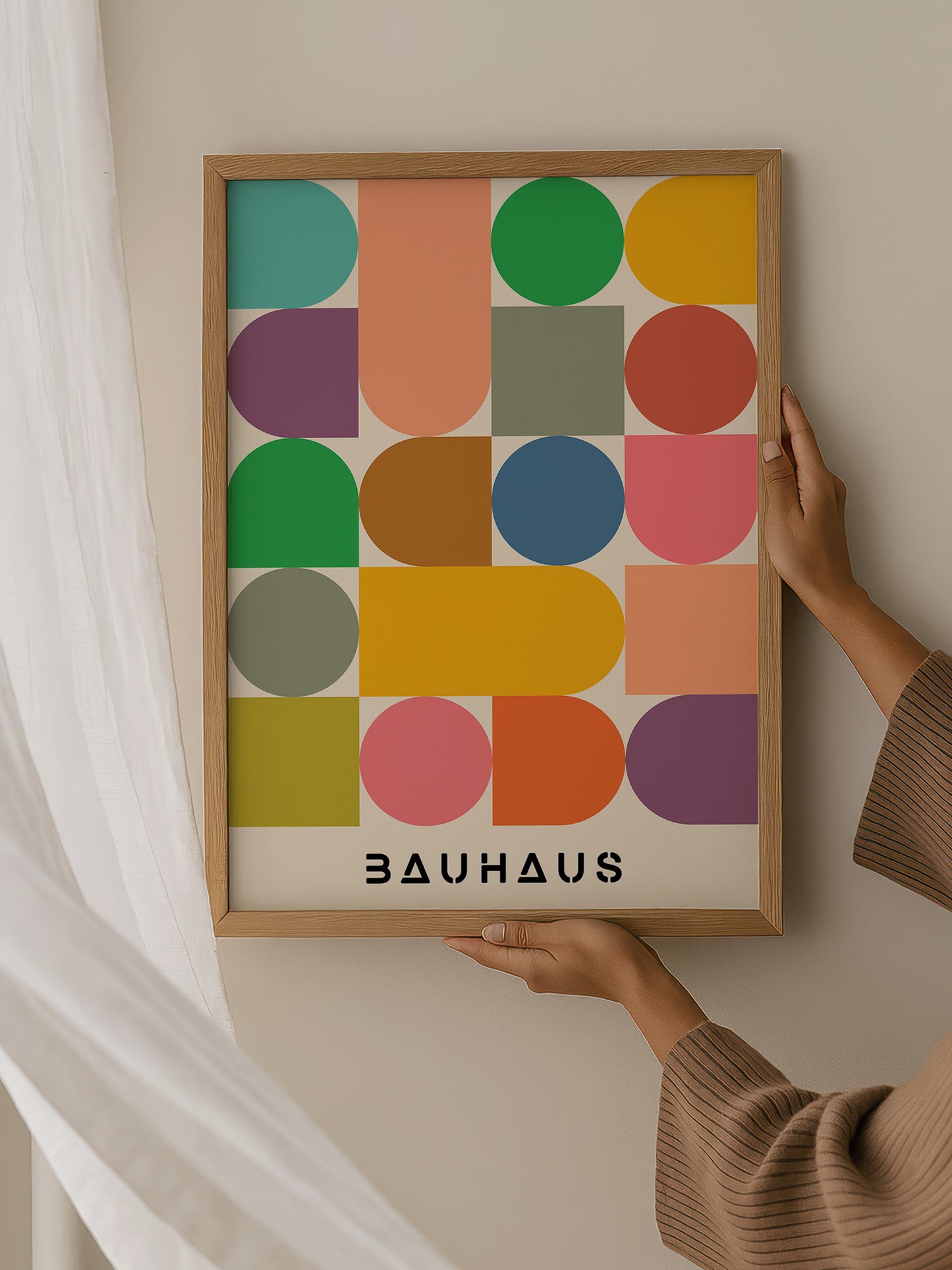 A person is holding up a framed poster with a colorful geometric design featuring various shapes and colors.