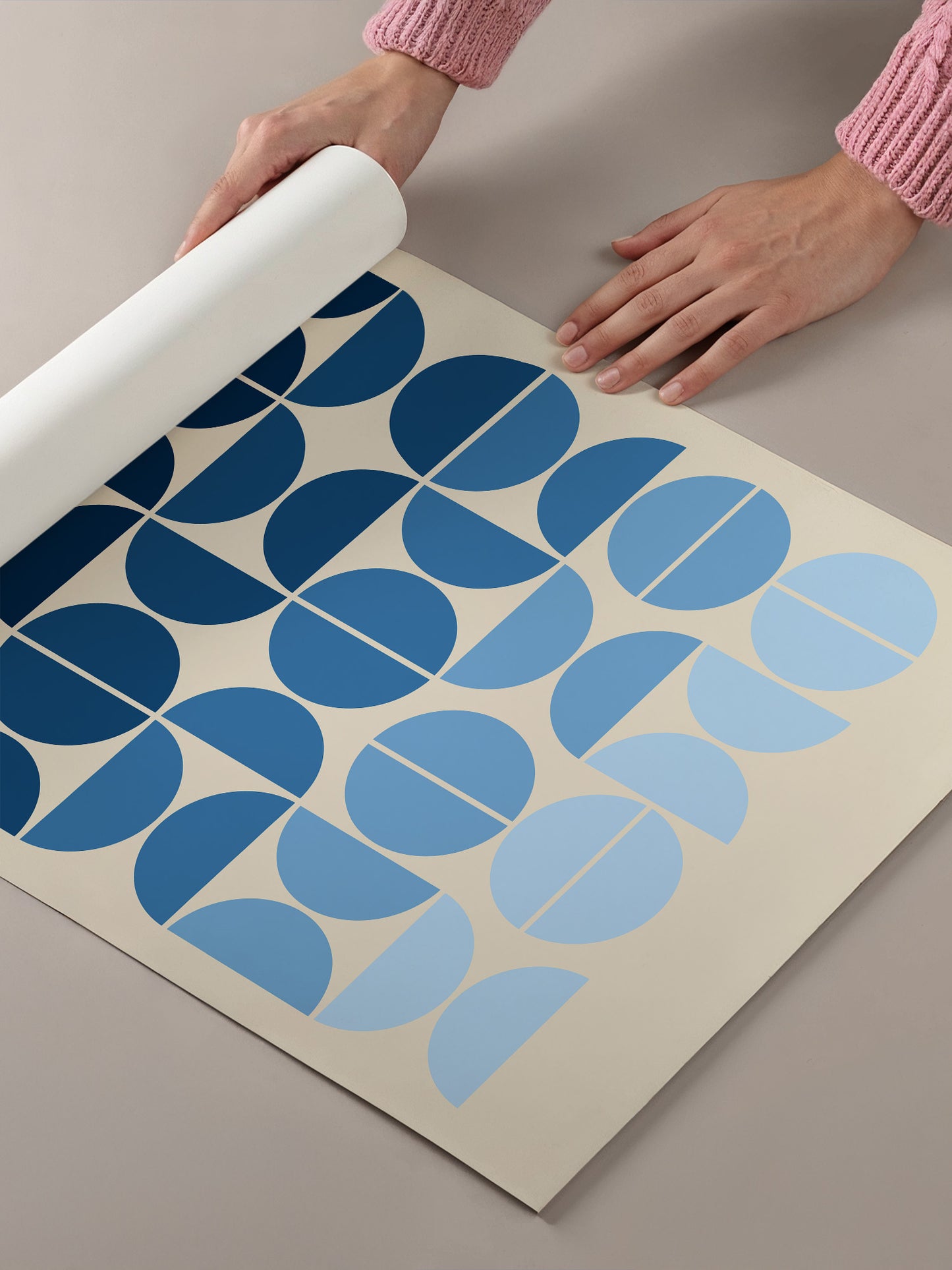 A person's hands are holding a roll of paper with a repeating pattern of blue and white circles on it.