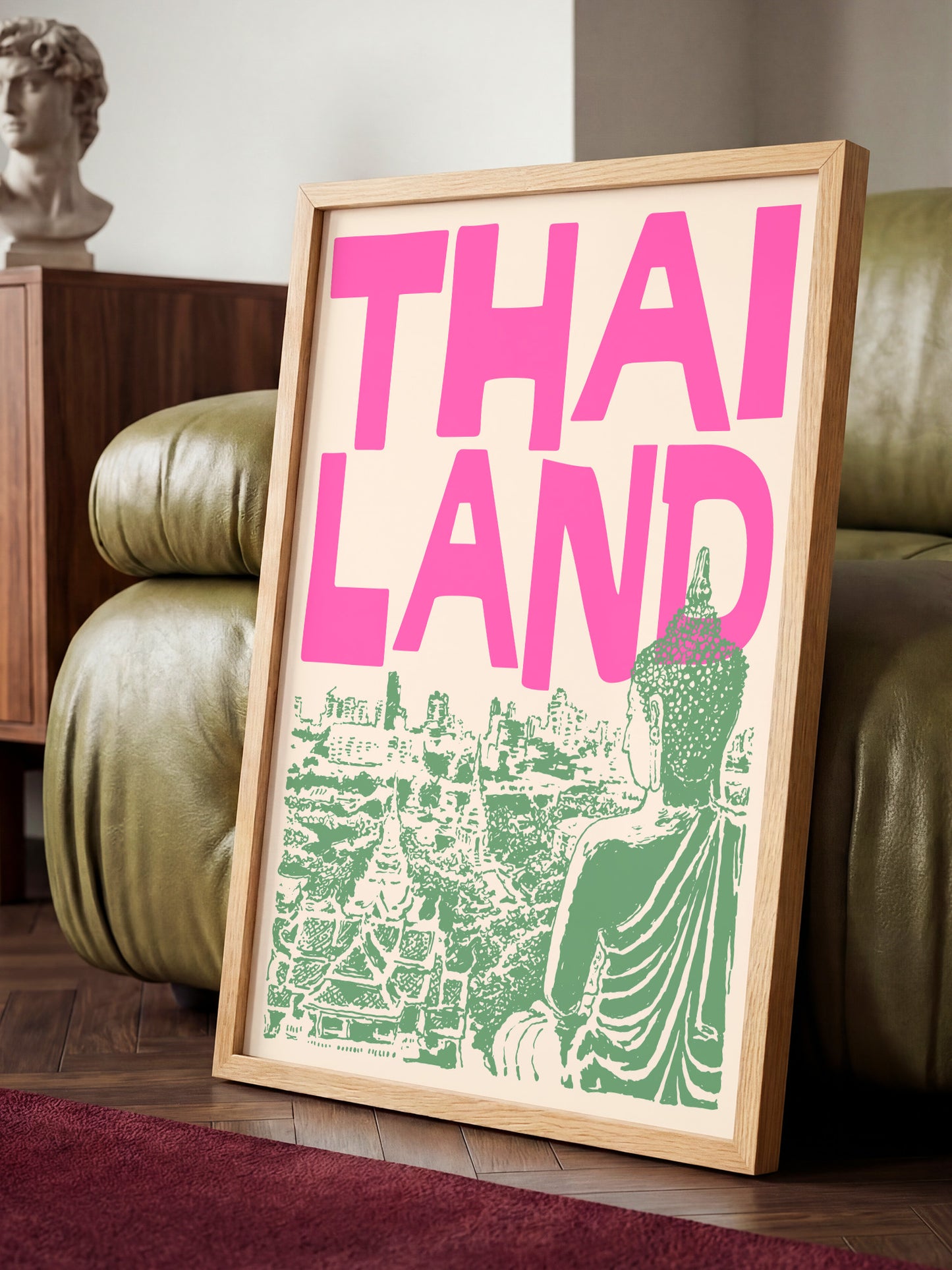 A framed poster with the text "THAI LANDS" in pink and green, featuring an illustration of a Buddha statue and a cityscape.