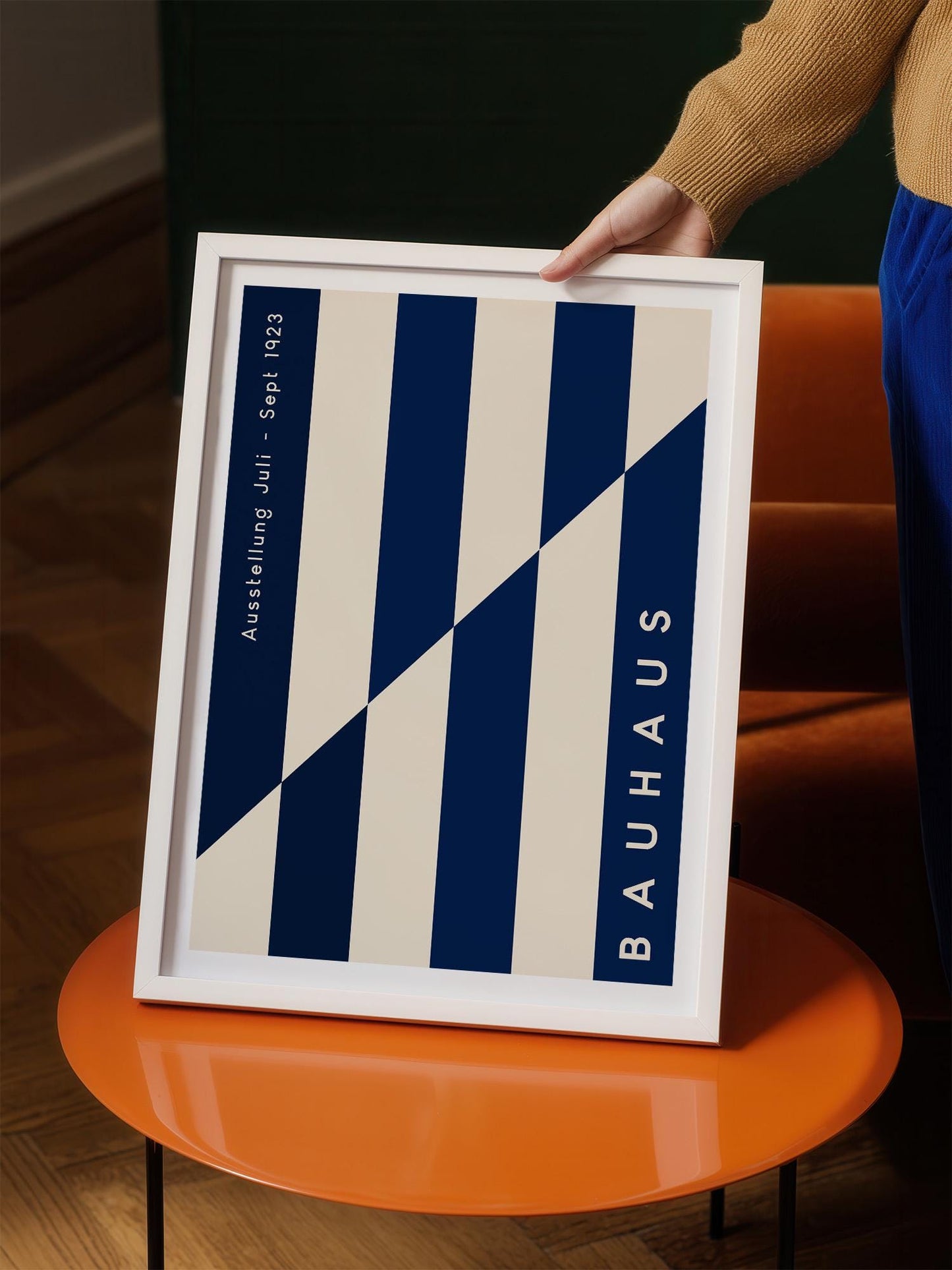 A person is holding a framed poster with a blue and white striped design.