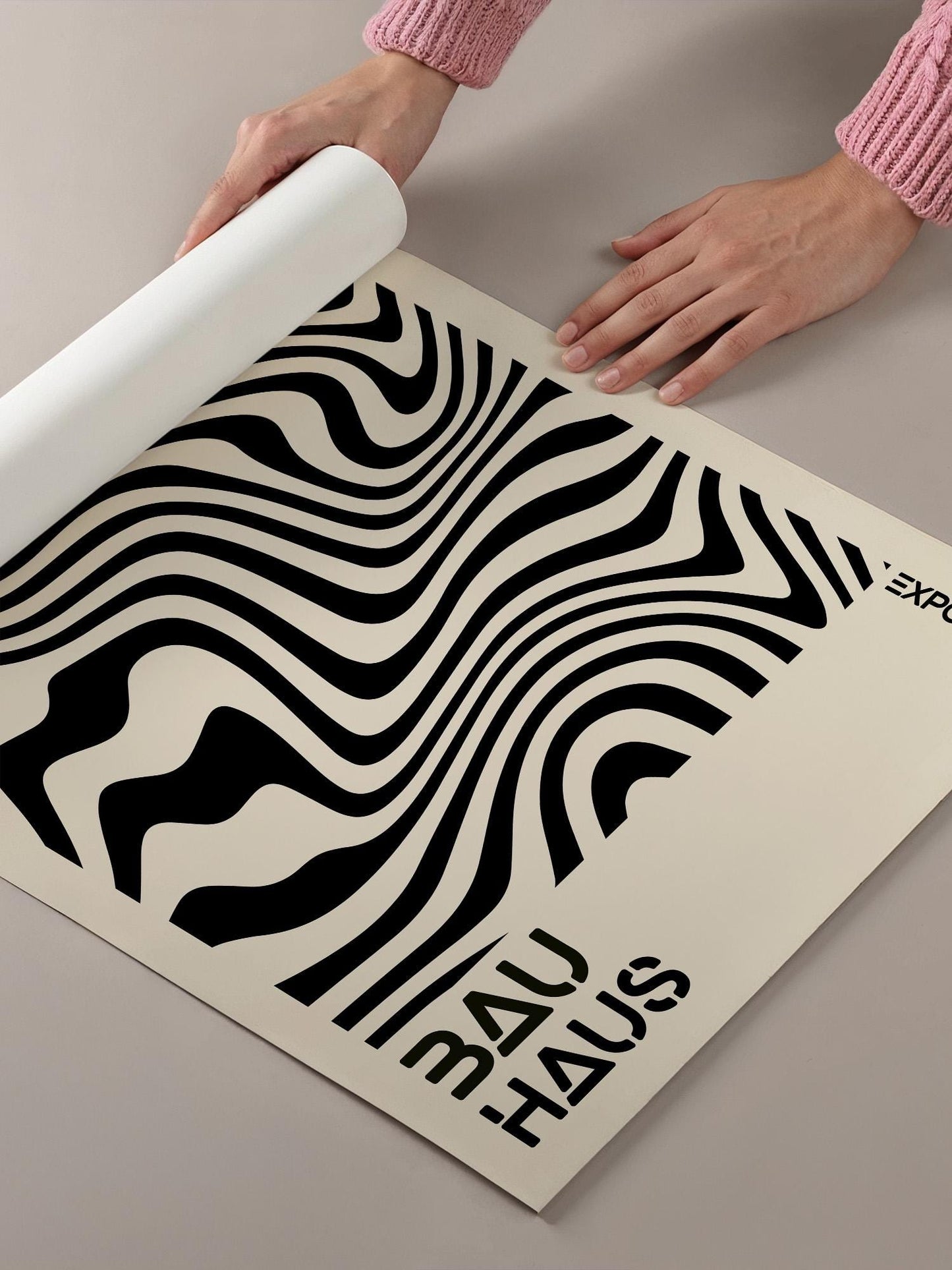 A person's hands are holding a roll of paper with a black and white abstract design printed on it.