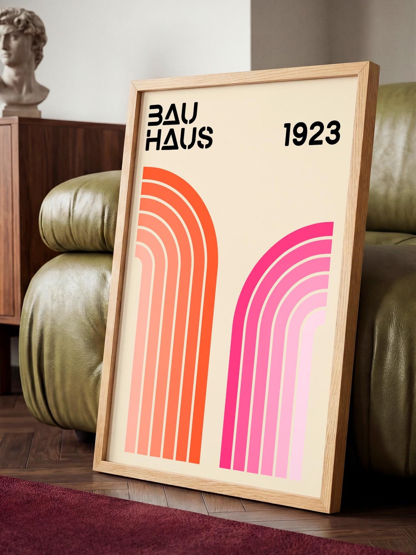 a framed poster with a minimalist design, displaying the text "BAU HAUS 1923" and two abstract geometric shapes in pink and orange.