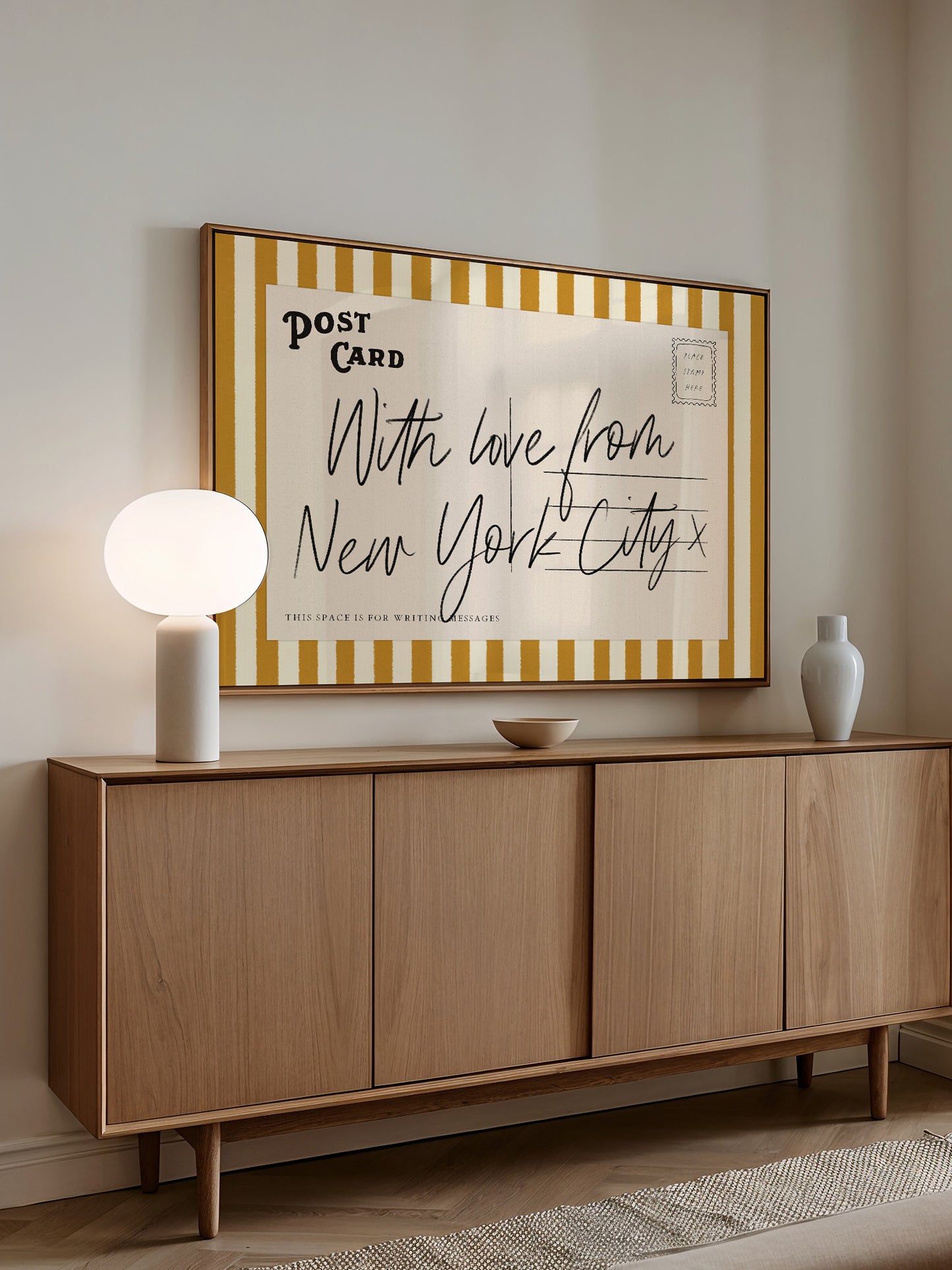a wooden cabinet with a framed poster on the wall above it. The poster has a handwritten message that reads "With love from New York City" and includes the words "This space is for writing."