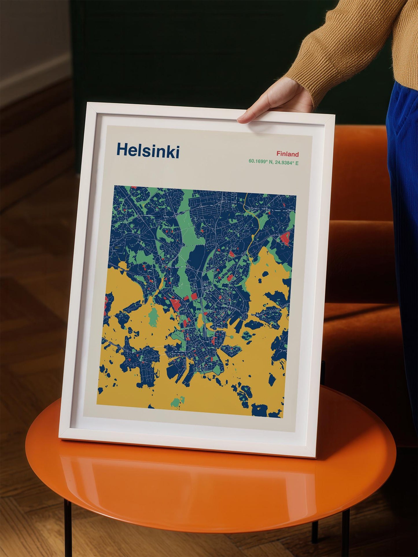 A person is holding a framed map of Helsinki, Finland, which is a colorful and detailed representation of the city.