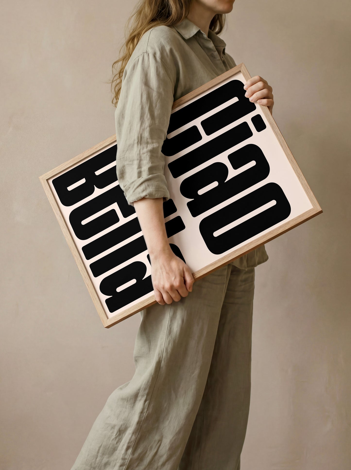A woman is standing and holding a large framed sign with bold black text on it.