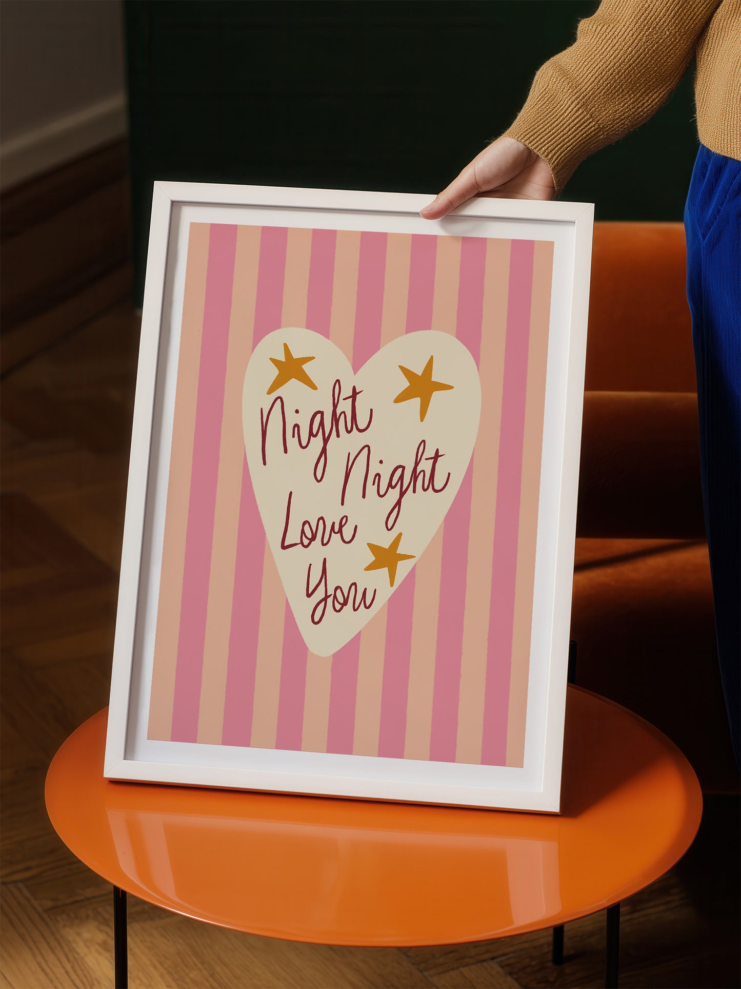 A person is holding up a framed poster with a heart-shaped design and text on it.