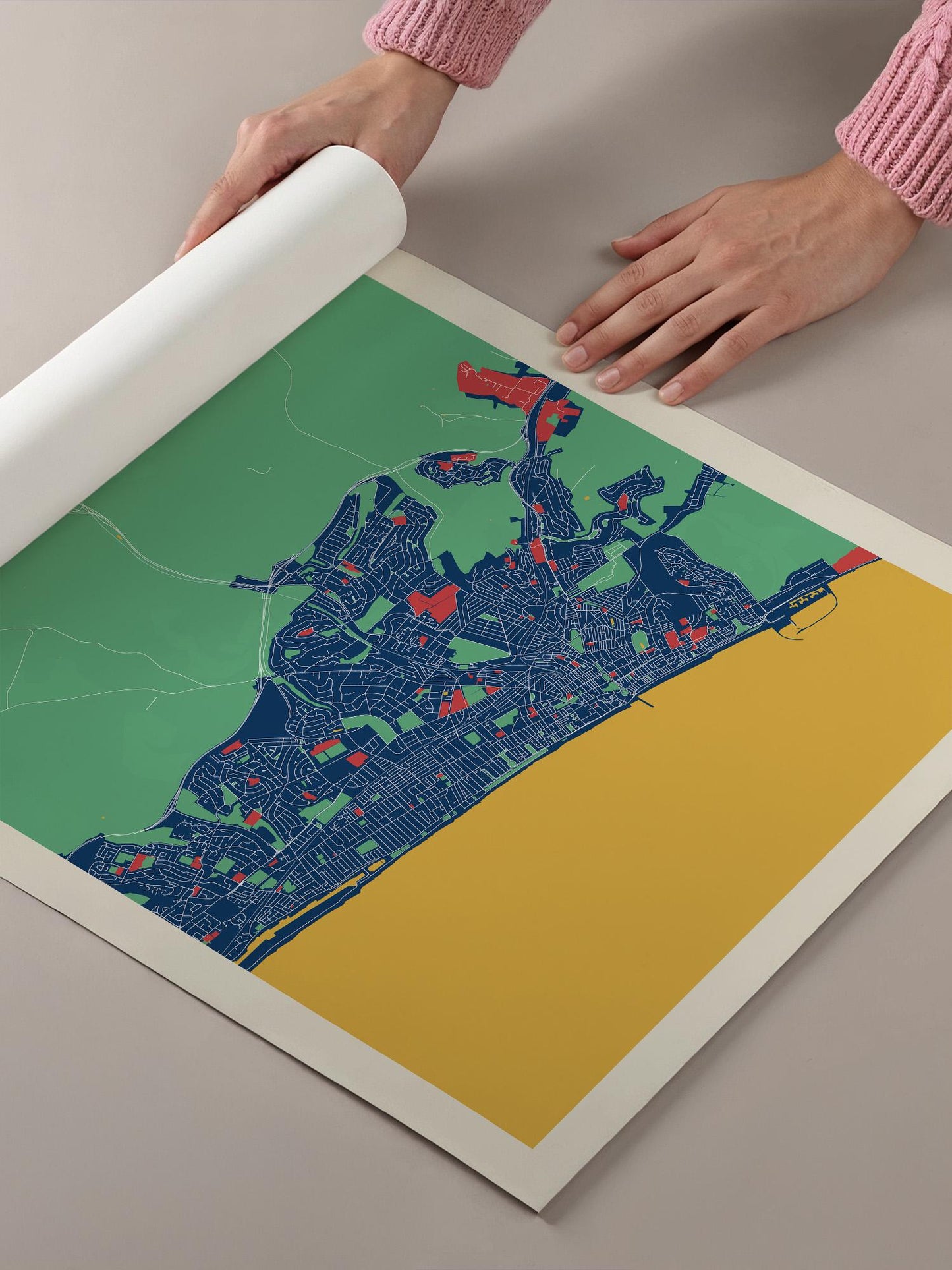 A person's hands are holding a roll of paper with a colorful map of a city printed on it.