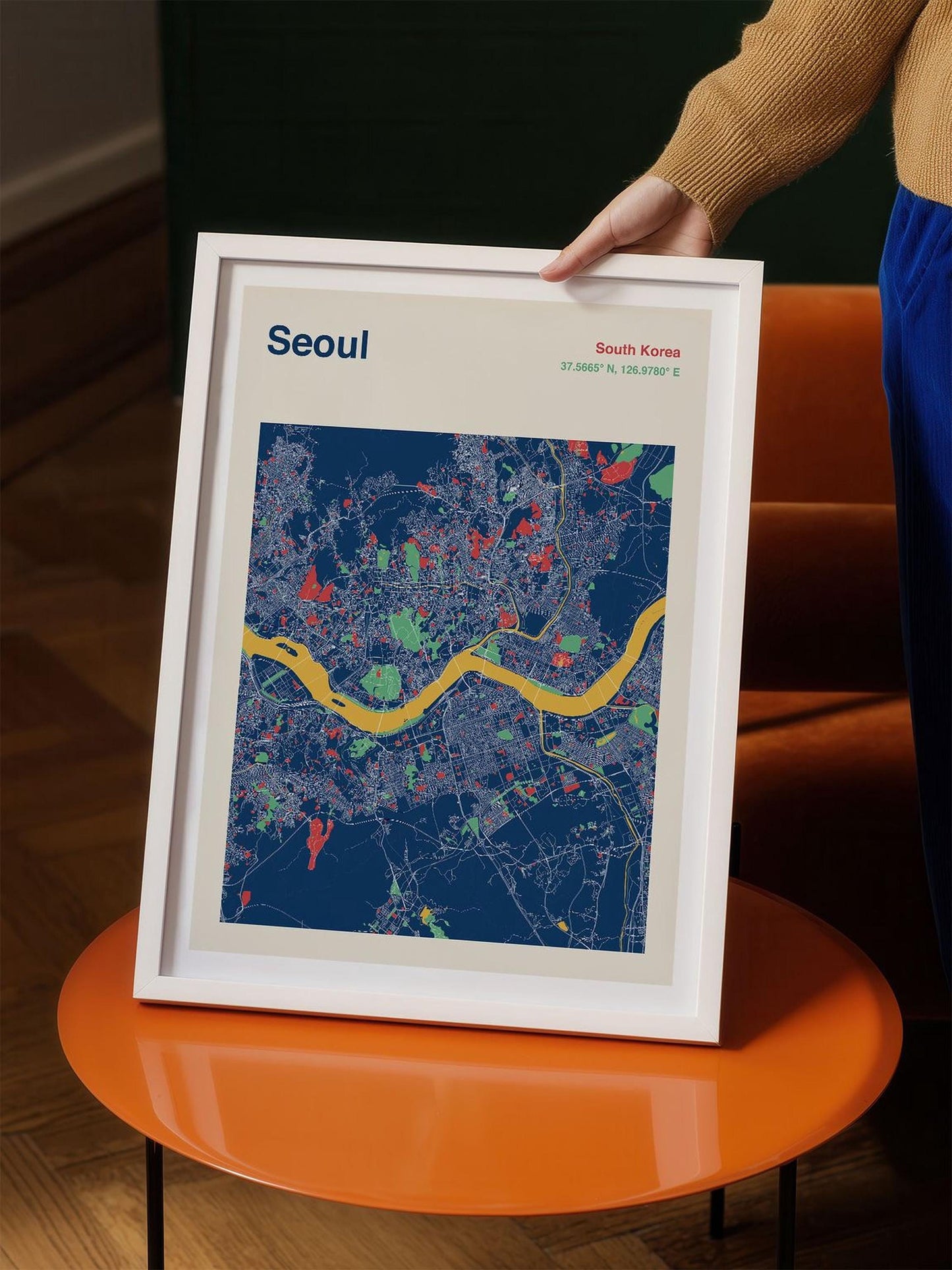 A person is holding a framed map of Seoul, South Korea, which features a colorful and detailed representation of the city's streets and landmarks.