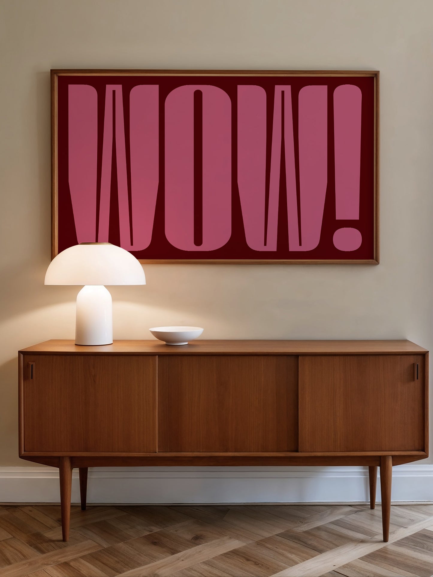a wooden cabinet with a white lamp on top, and a large framed text in pink on the wall above the cabinet.