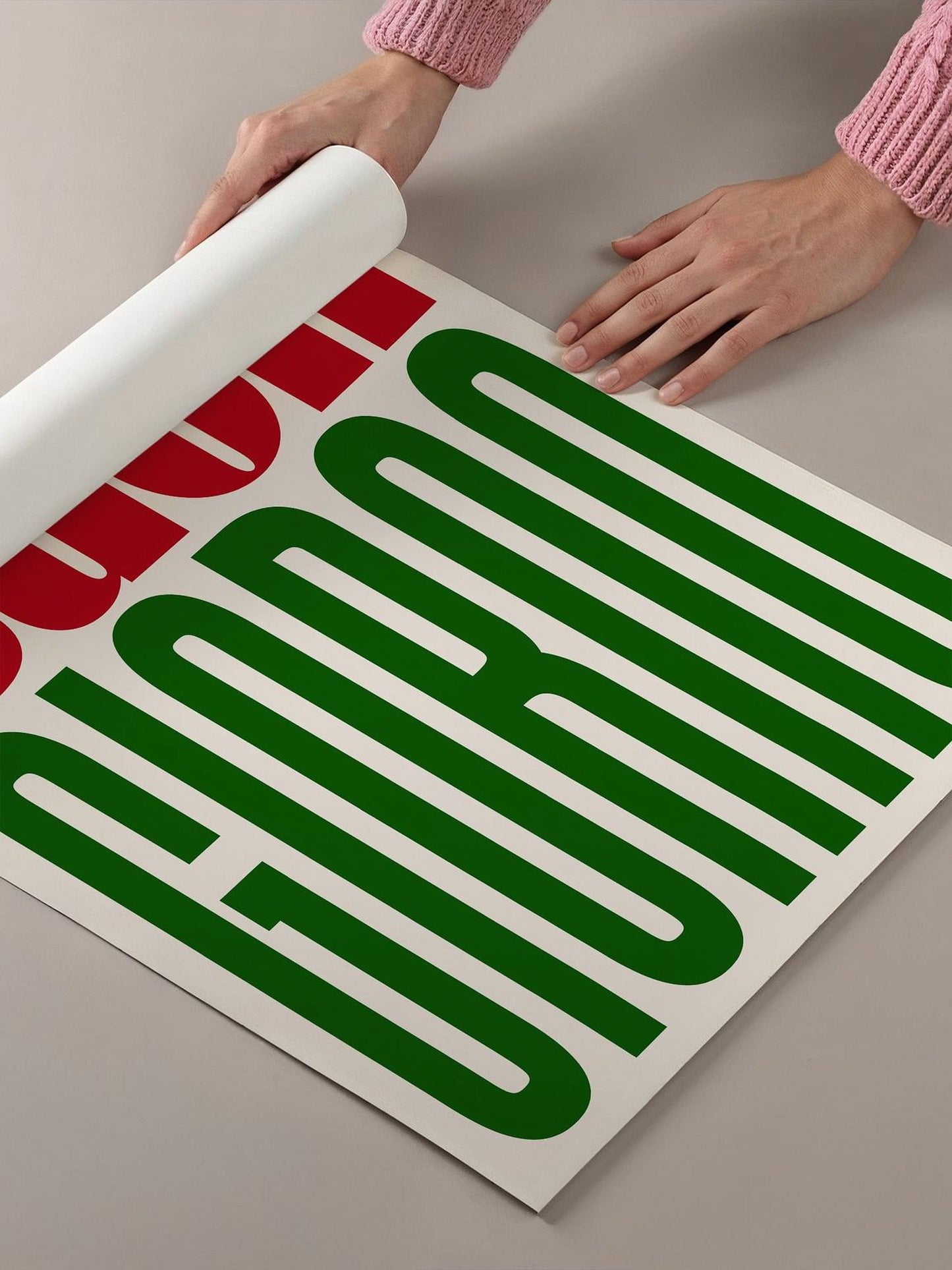 a person's hands holding a roll of paper, which appears to be a poster or a sign with large green text on it.