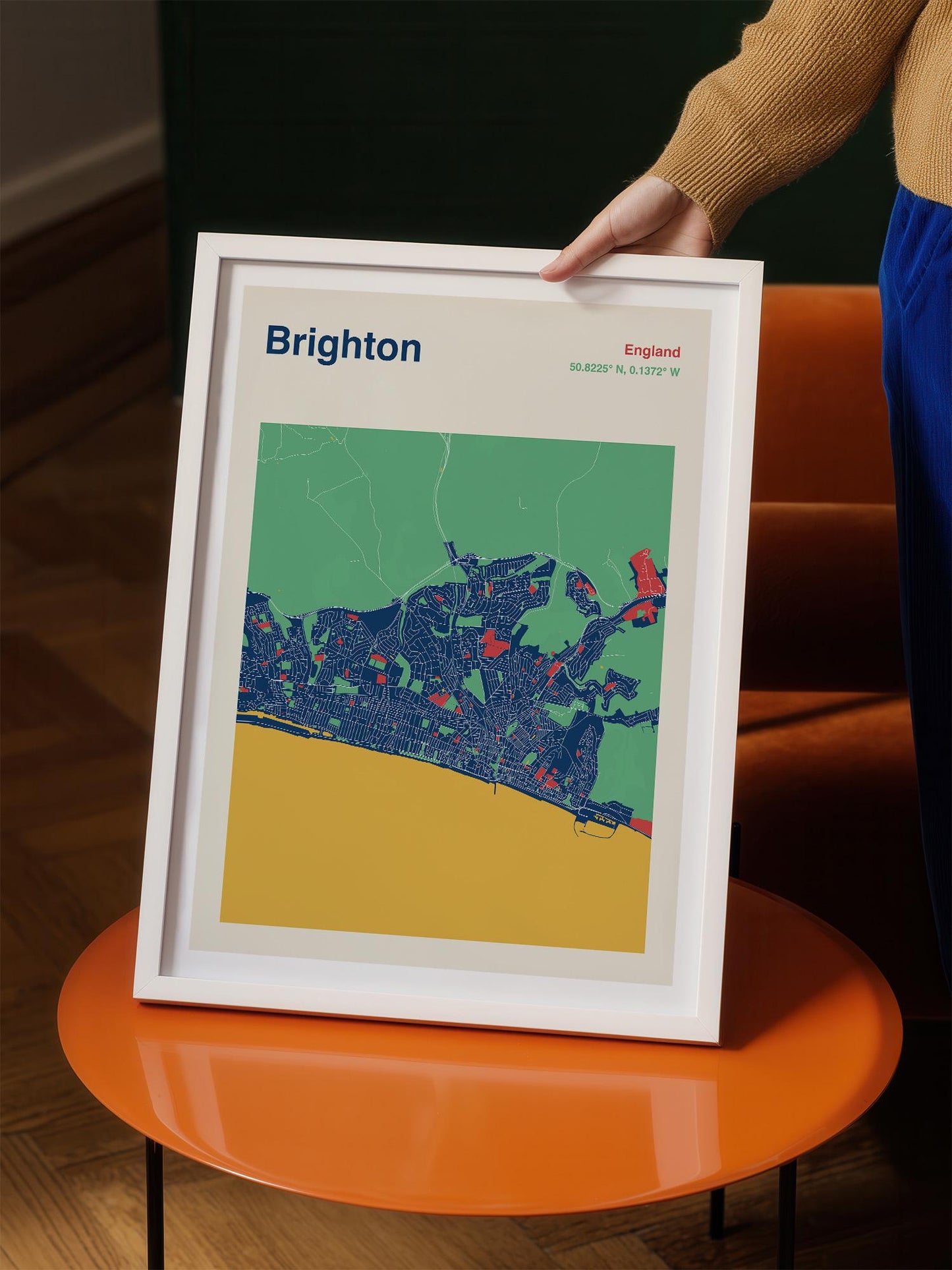 A person is holding a framed poster of Brighton, England, with a colorful map and text.