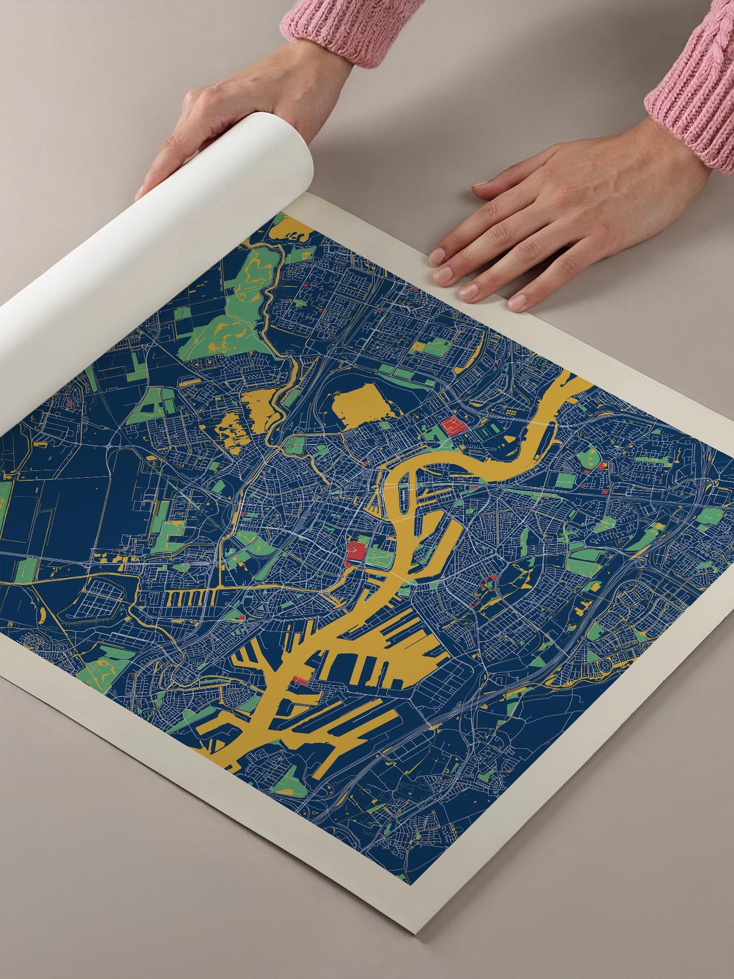 A person's hands are holding a roll of paper, which appears to be a map or a printed image, with a blue and yellow color scheme.