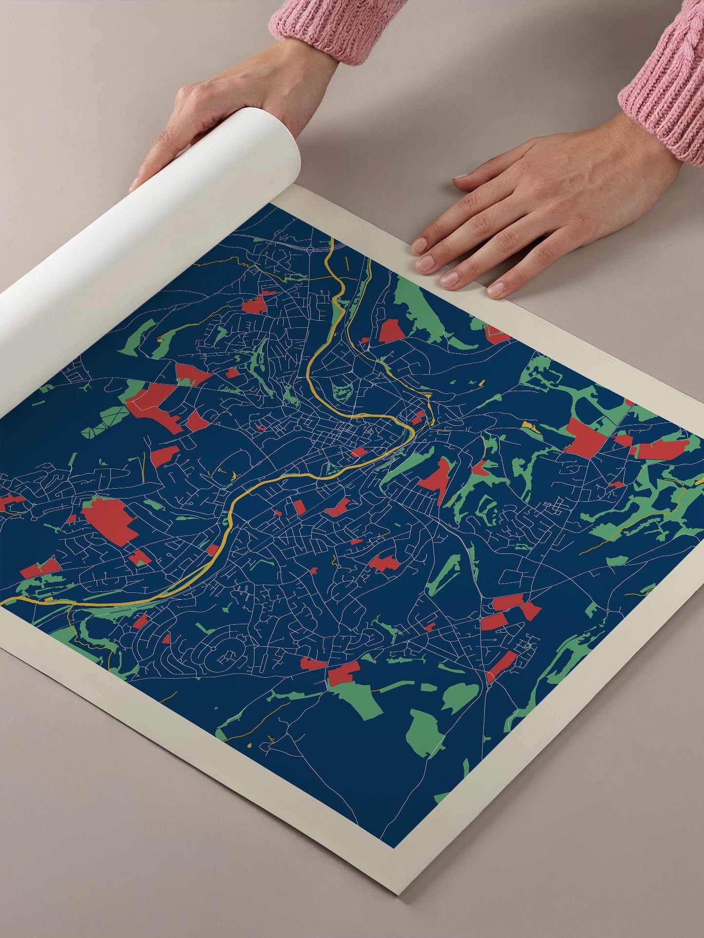 A person's hands are holding a roll of paper, which is displaying a colorful map of a city or region.