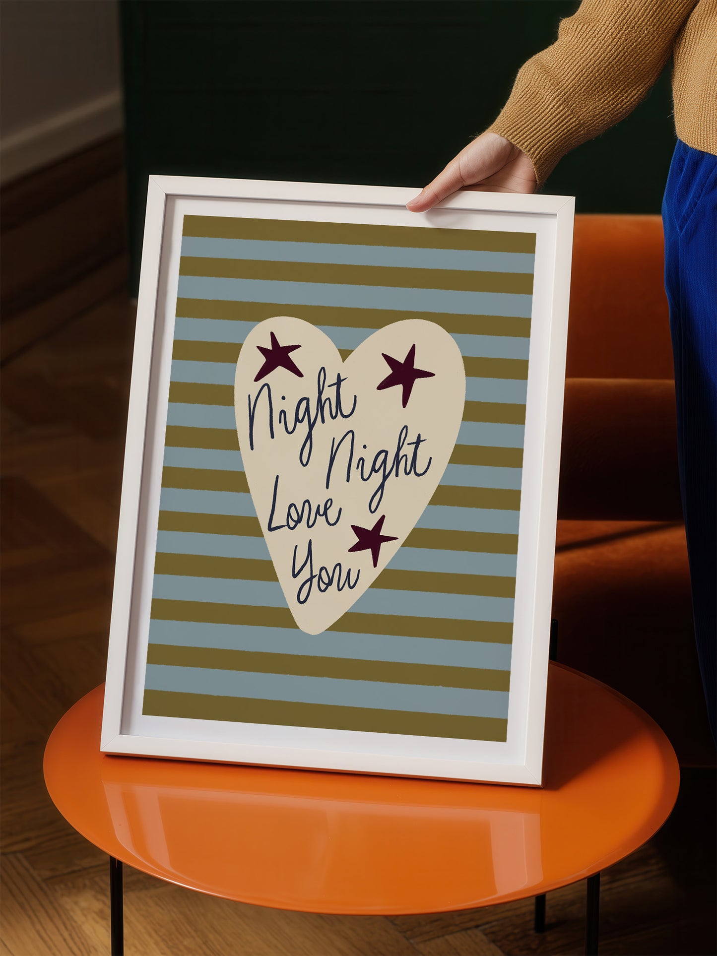 A person is holding a framed picture with a heart-shaped design and the text "Night Night Love You" written on it.