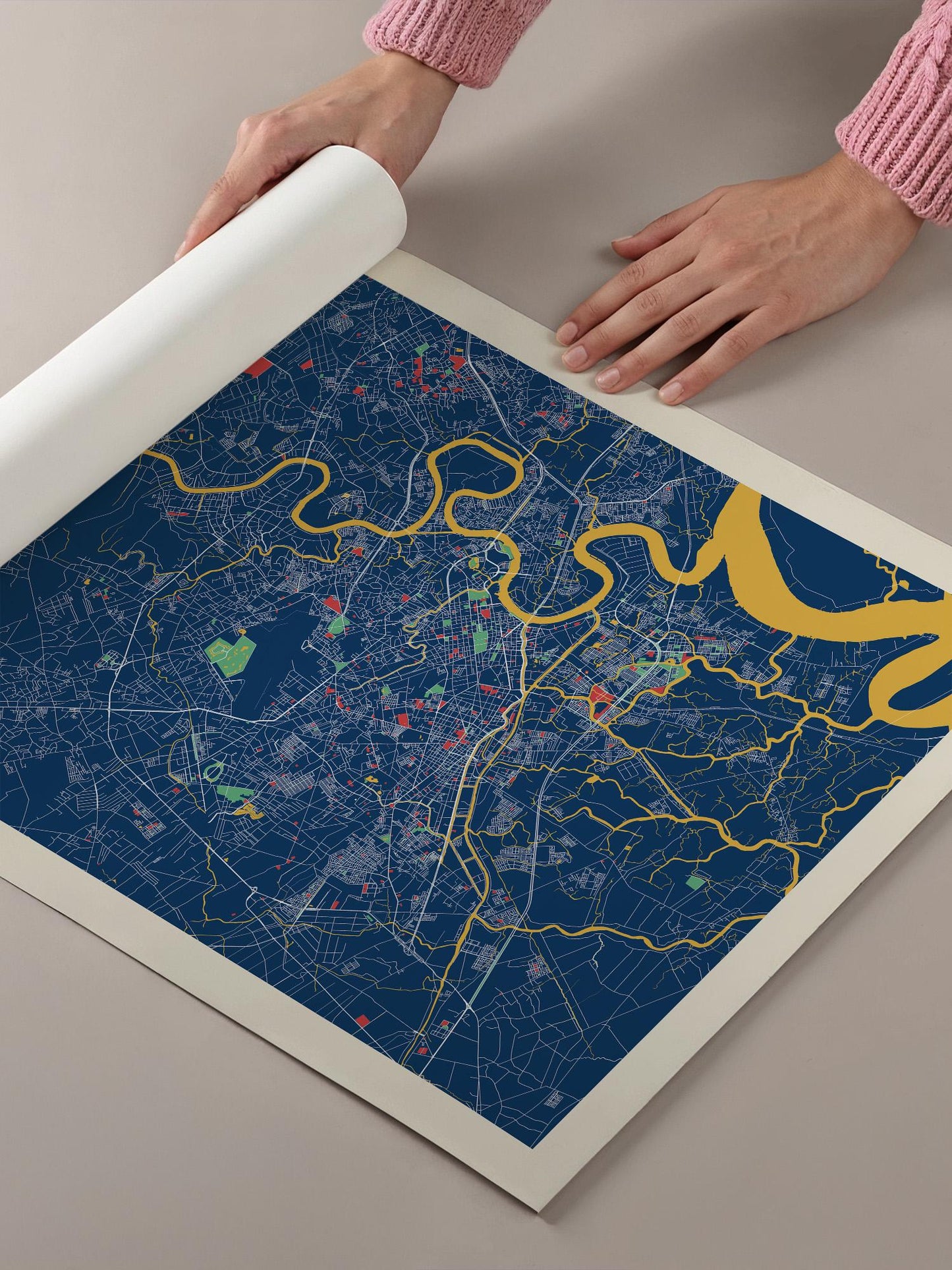 A person's hands are holding a large, colorful map of a city, with various streets and landmarks depicted on the map.