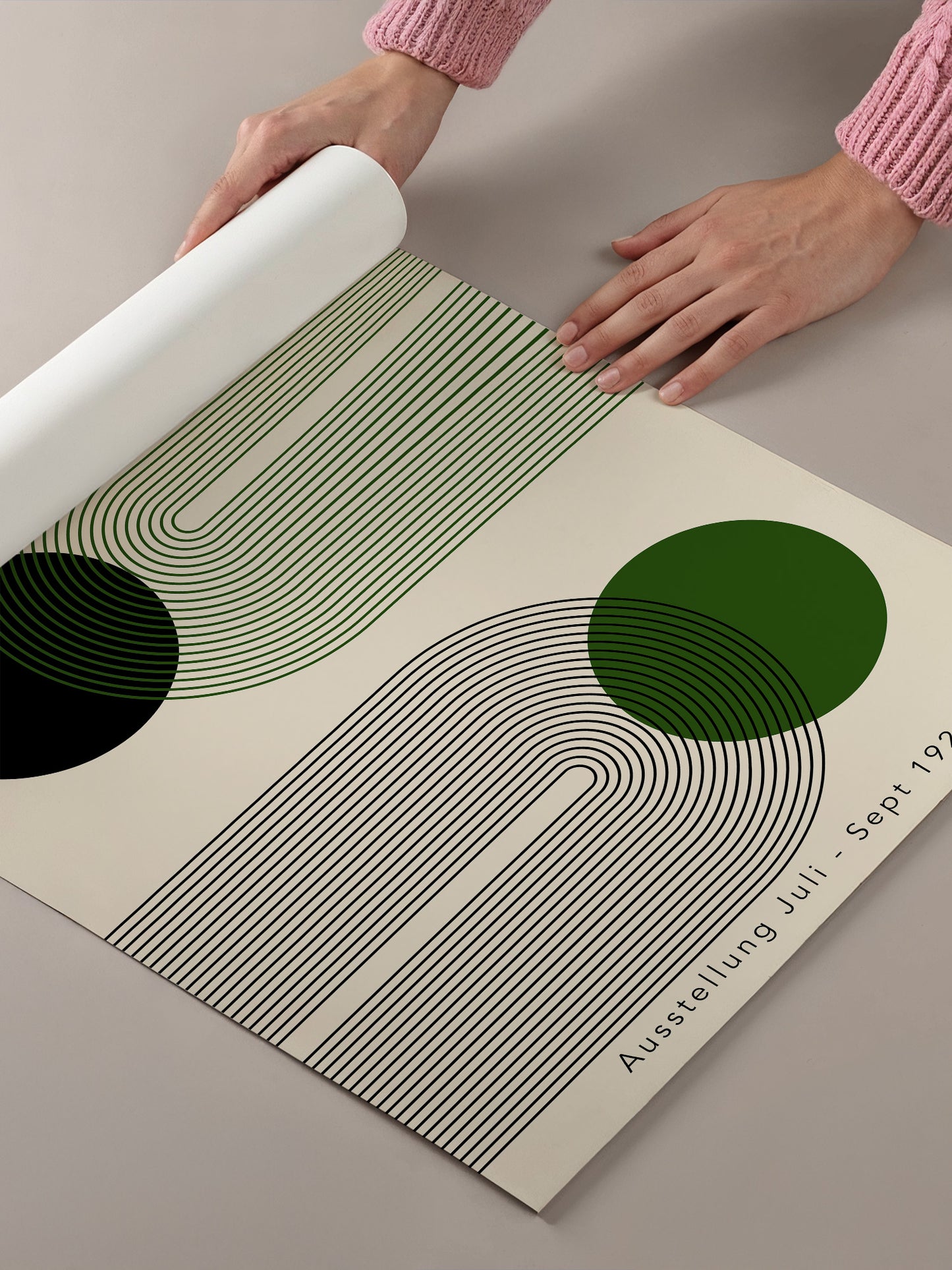 A person's hands are holding a roll of paper with a geometric design featuring green and black lines and circles.