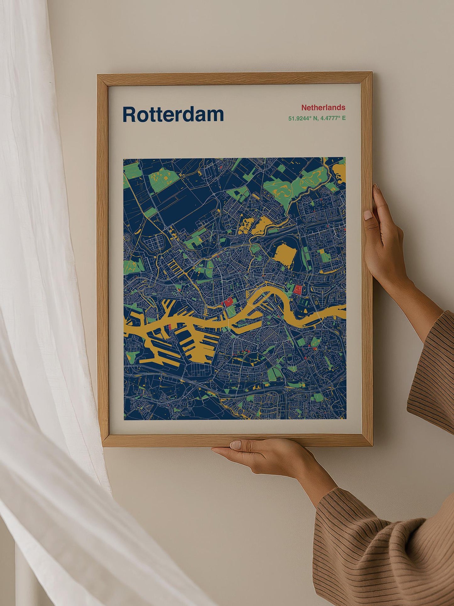 A person is holding up a framed map of Rotterdam, Netherlands, which is a colorful and detailed representation of the city.