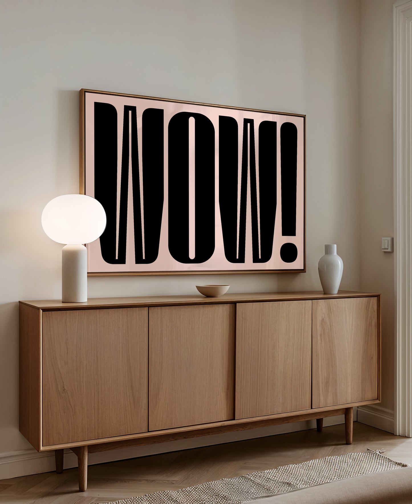 a modern interior design with a large wooden cabinet or sideboard, a white lamp, and a framed artwork with bold black text on the wall.