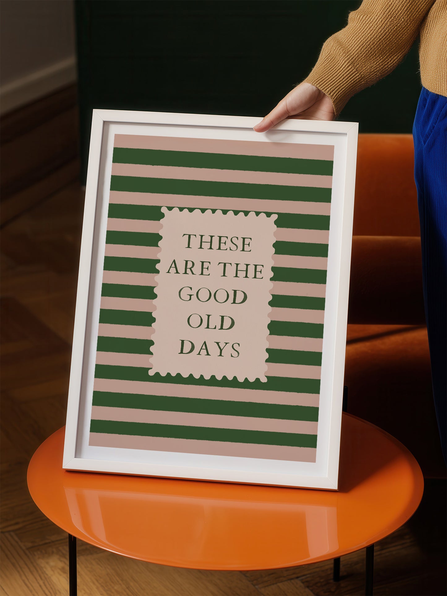 A person is holding up a framed poster with the text "These are the good old days" on it.