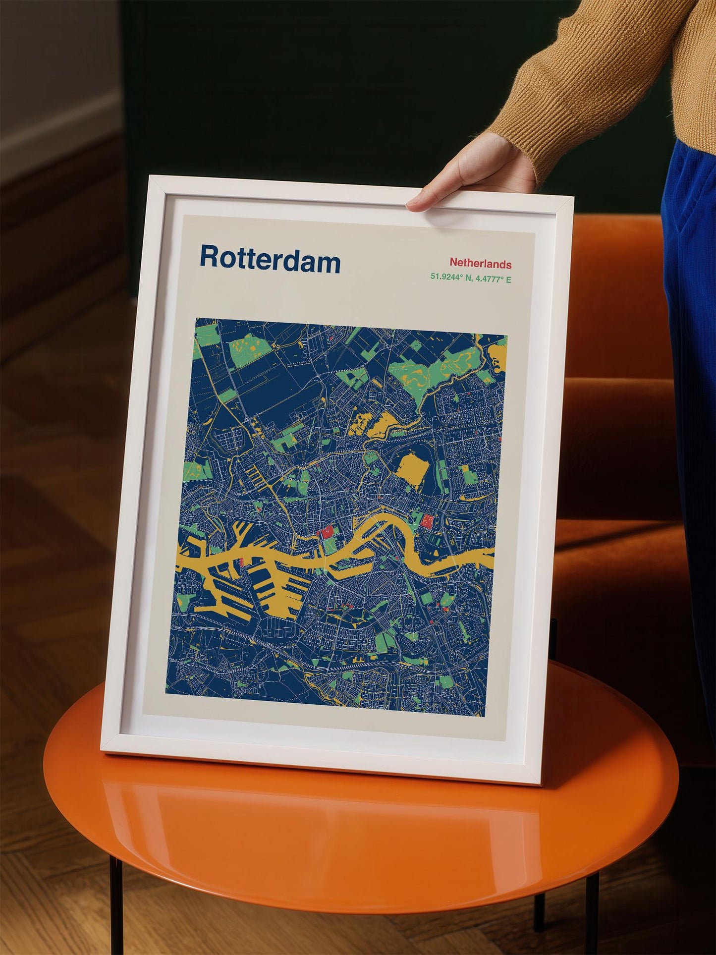 A person is holding a framed map of Rotterdam, Netherlands, which features a colorful and detailed map of the city.