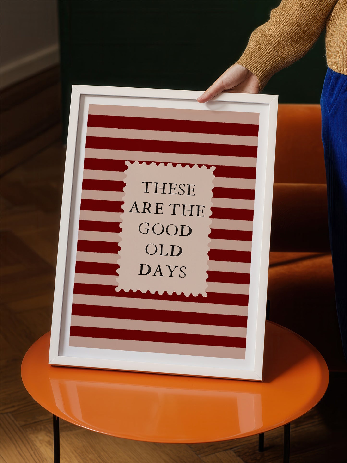 A person is holding a framed poster with the text "These are the good old days" on it.