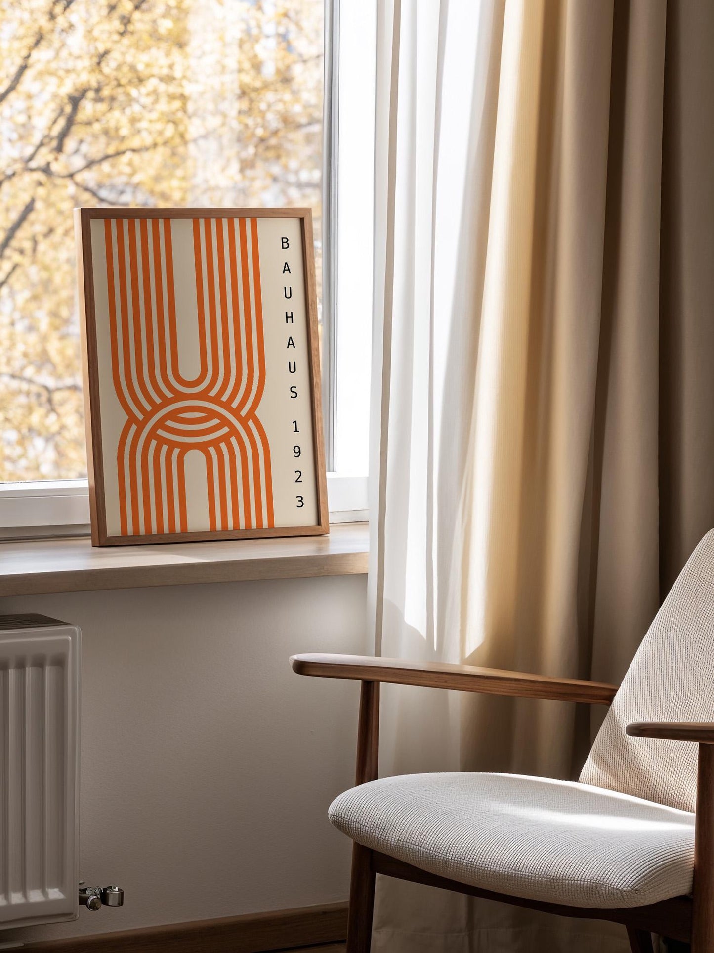a framed poster of the Bauhaus design style, placed on a window sill next to a chair.