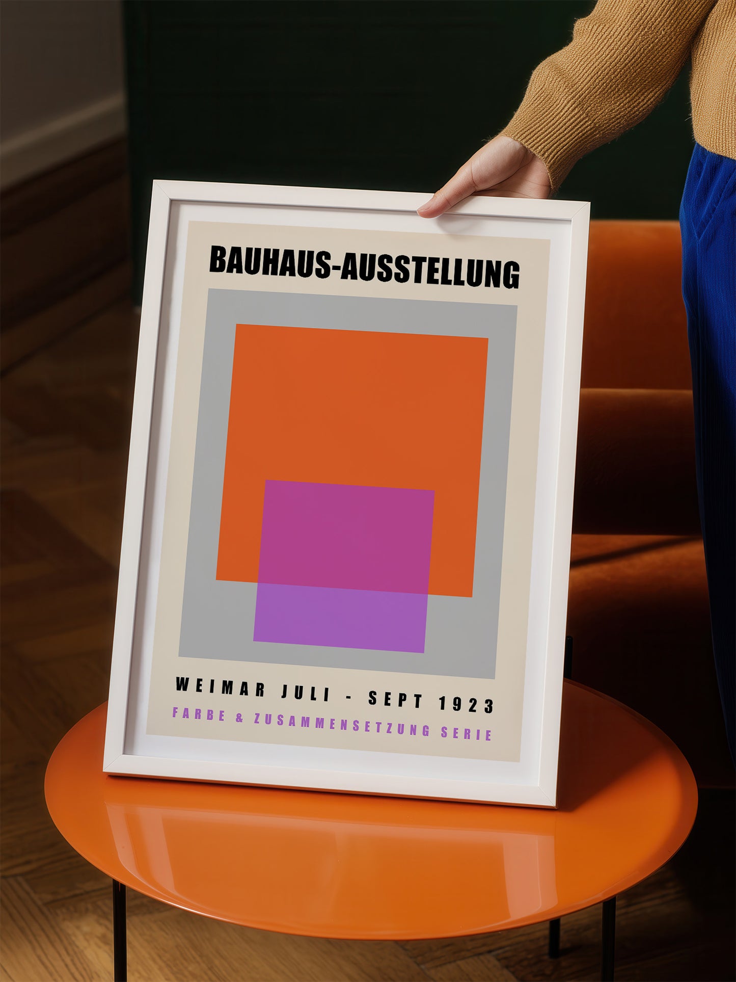 A person is holding up a framed poster with the text "BAHAUX-AUSSTELLUNG" and "WEIMAR JULI - SEPT 1923" printed on it.