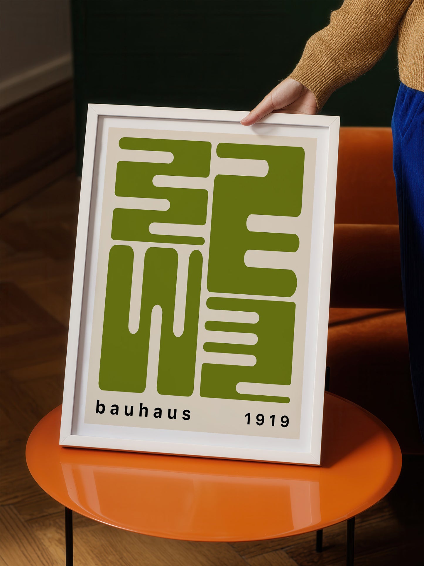 A person is holding a framed poster with a large green geometric design and the text "bauhaus 1919" on it.
