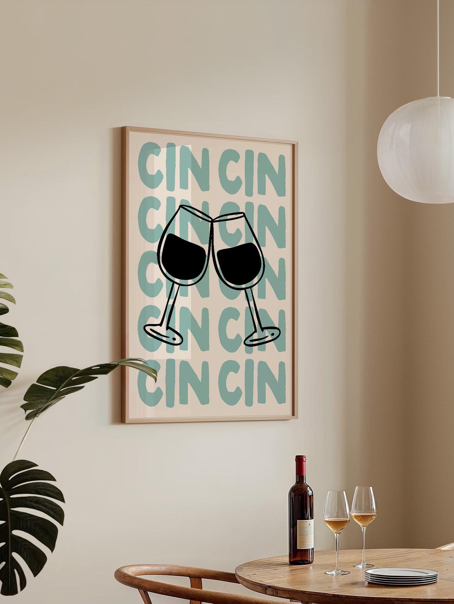 a framed poster with the phrase "CIN CON CIN" on it, along with two wine glasses depicted in the poster. There is a bottle of wine and two glasses on a table in the foreground, suggesting a social setting or a celebration.