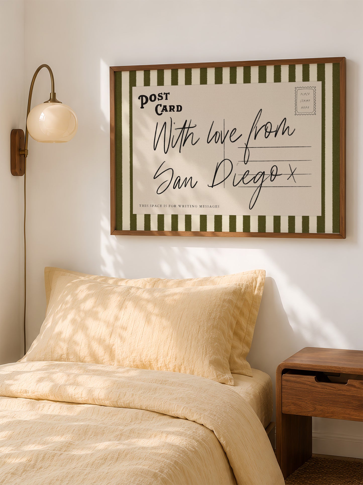 a bedroom with a bed, a nightstand, and a framed postcard hanging on the wall.