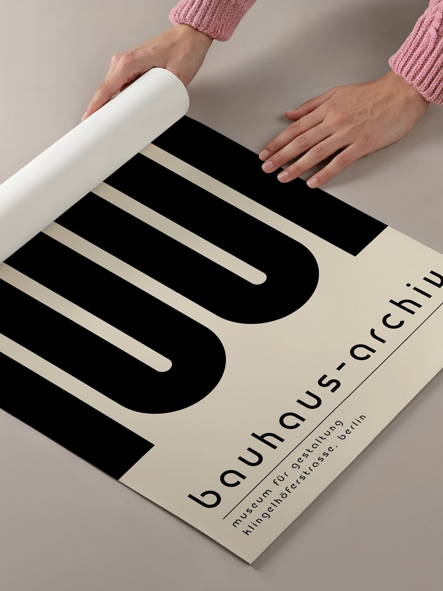 A person's hands are holding a roll of paper, which appears to be a poster or sign for the Bauhaus-architecture museum in Berlin.