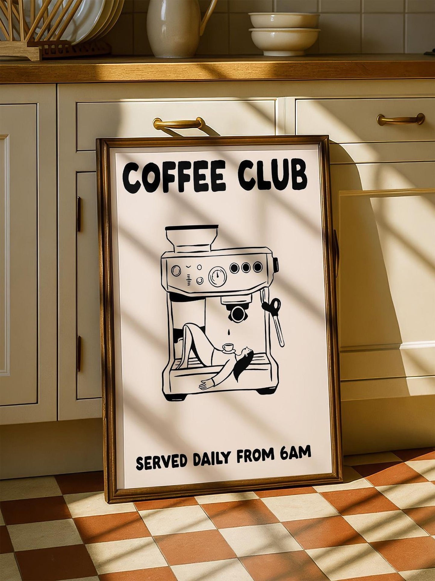 A framed poster with the text "COFFEE CLUB" and an illustration of a coffee machine, placed on a checkered floor in a kitchen.