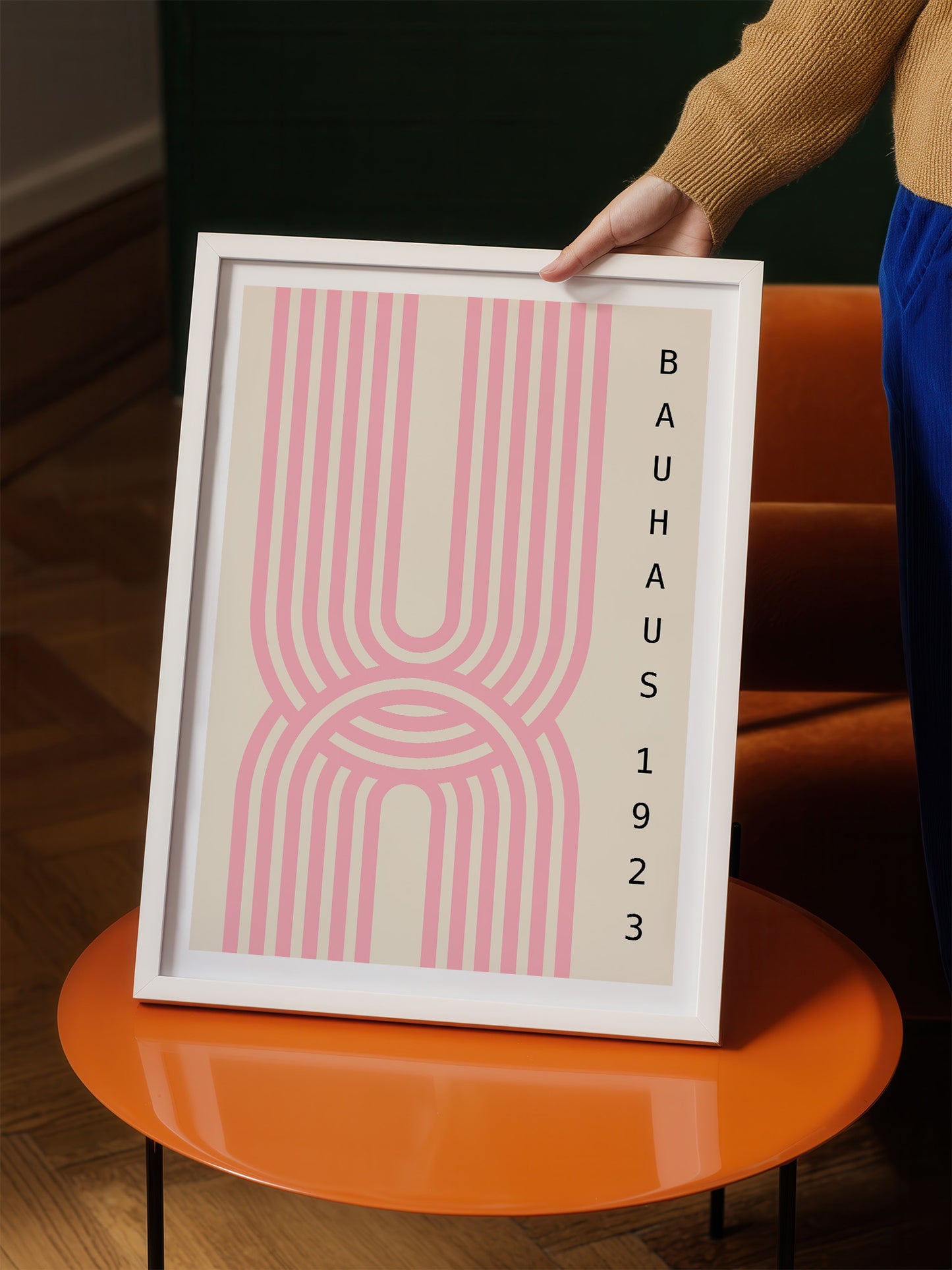 A person is holding a framed poster with a pink and white abstract design.