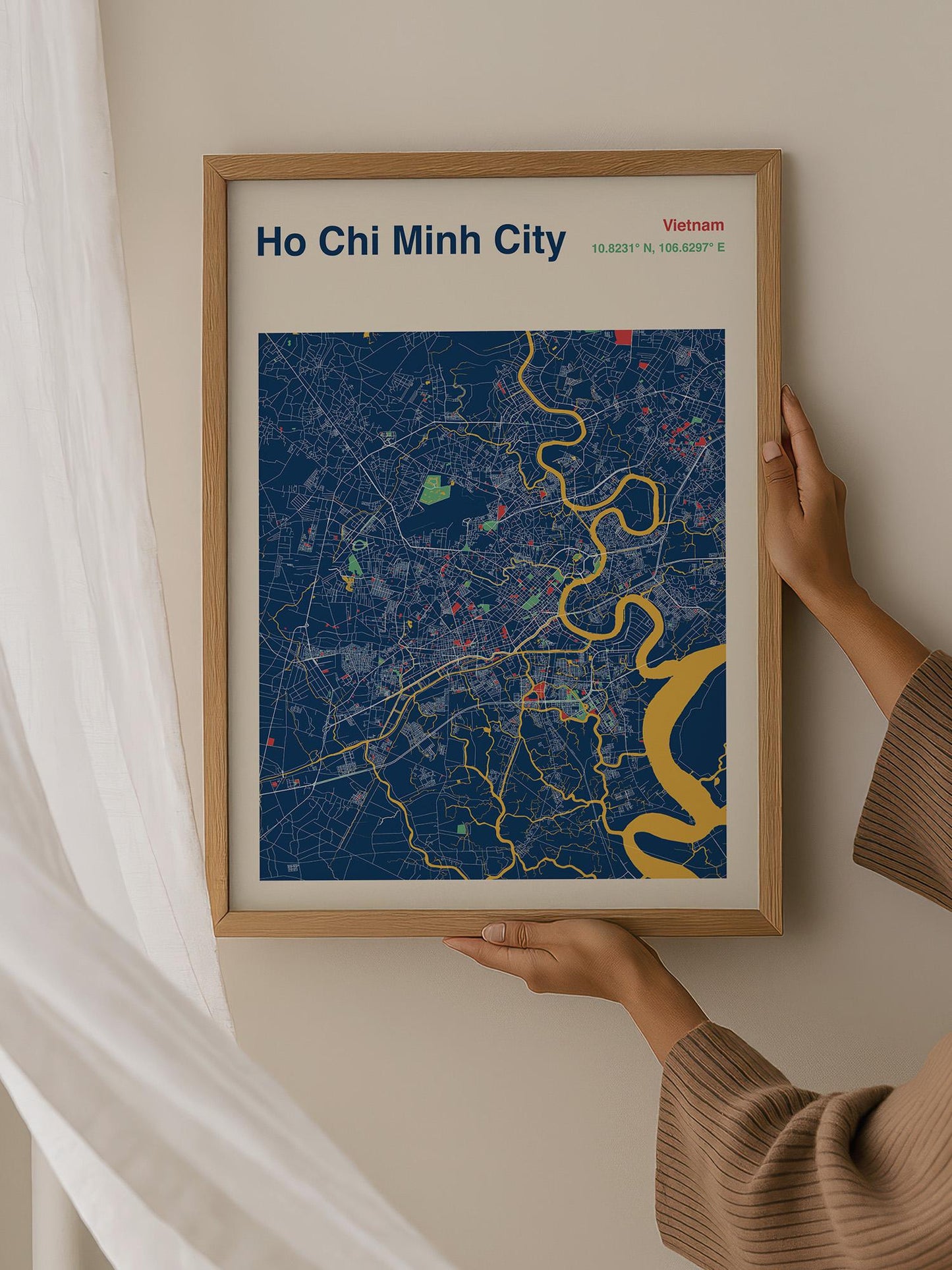 A person is holding up a framed map of Ho Chi Minh City, Vietnam, which features a colorful and detailed representation of the city's streets and landmarks.