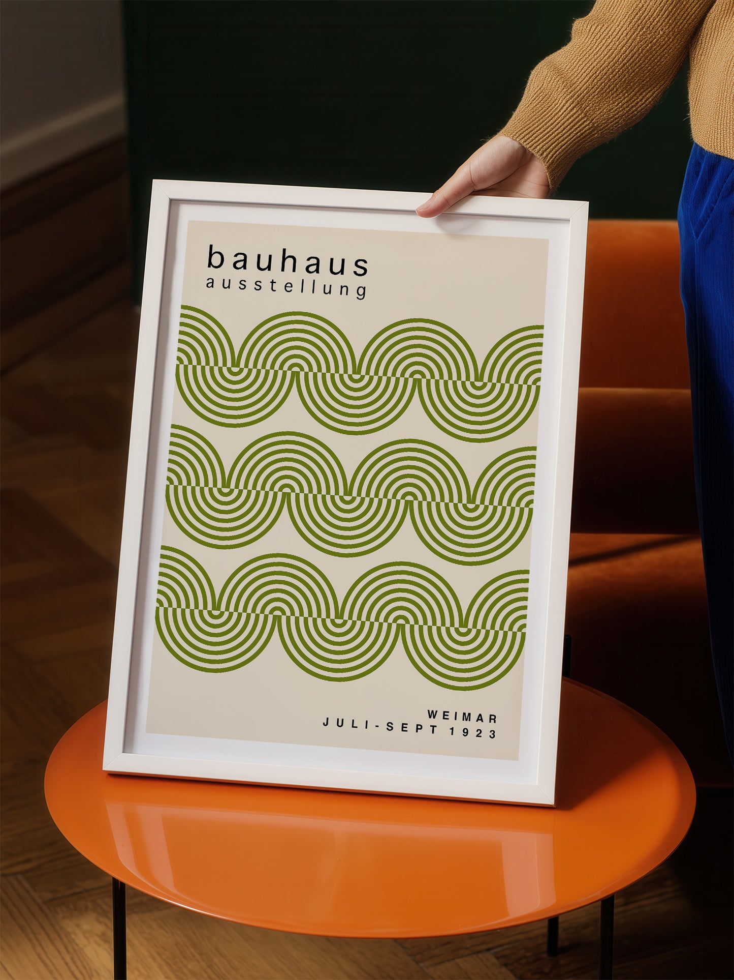 A person is holding a framed poster with a repeating pattern of green and white swirls.