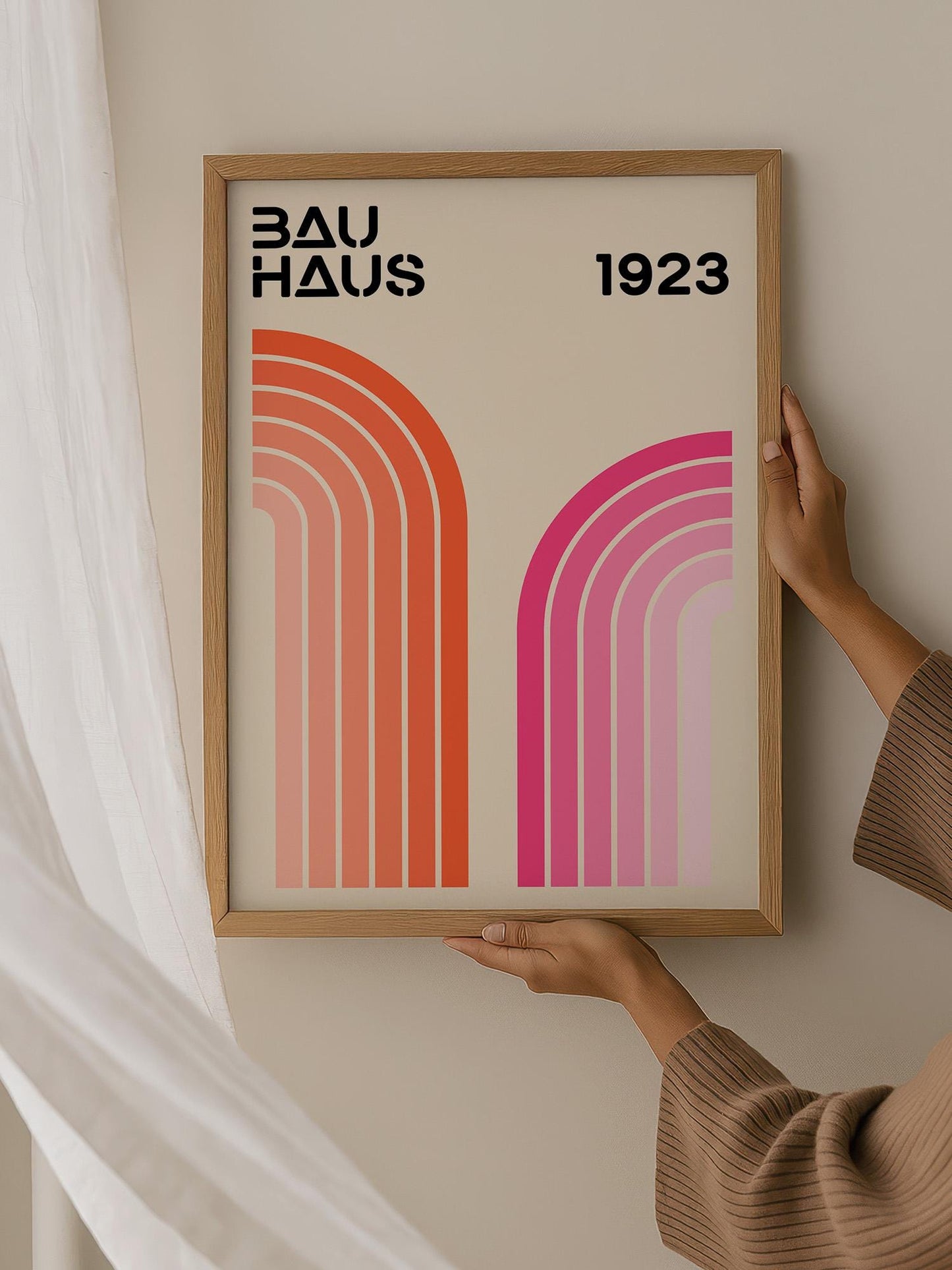 A person is holding up a framed poster with the text "BAU HAUS 1923" on it.