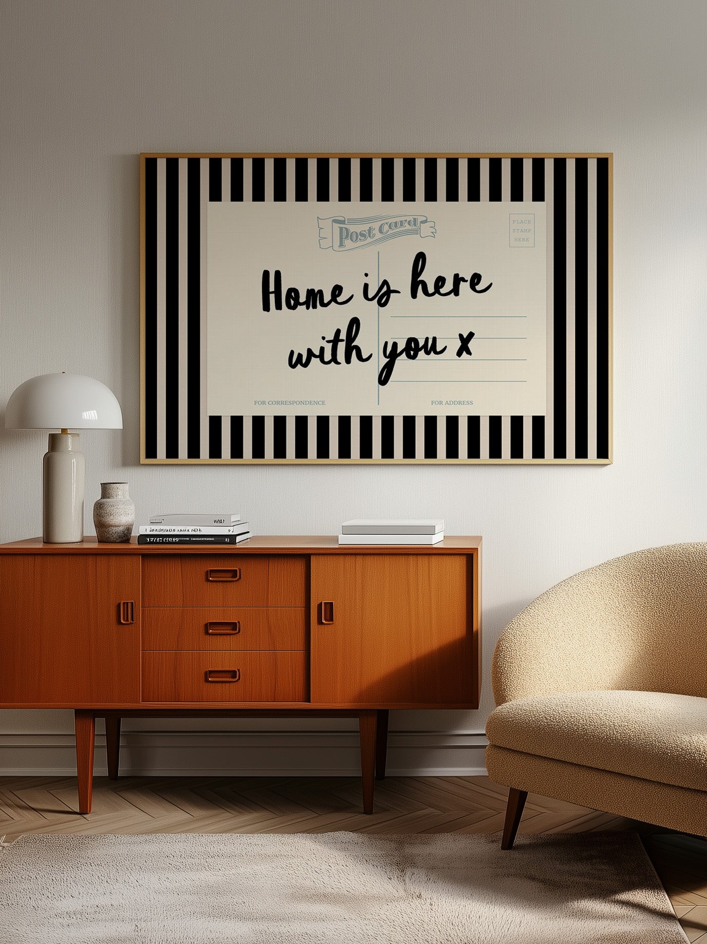 a living room with a wooden cabinet, a beige armchair, and a framed poster on the wall that reads "Home is here with you x".