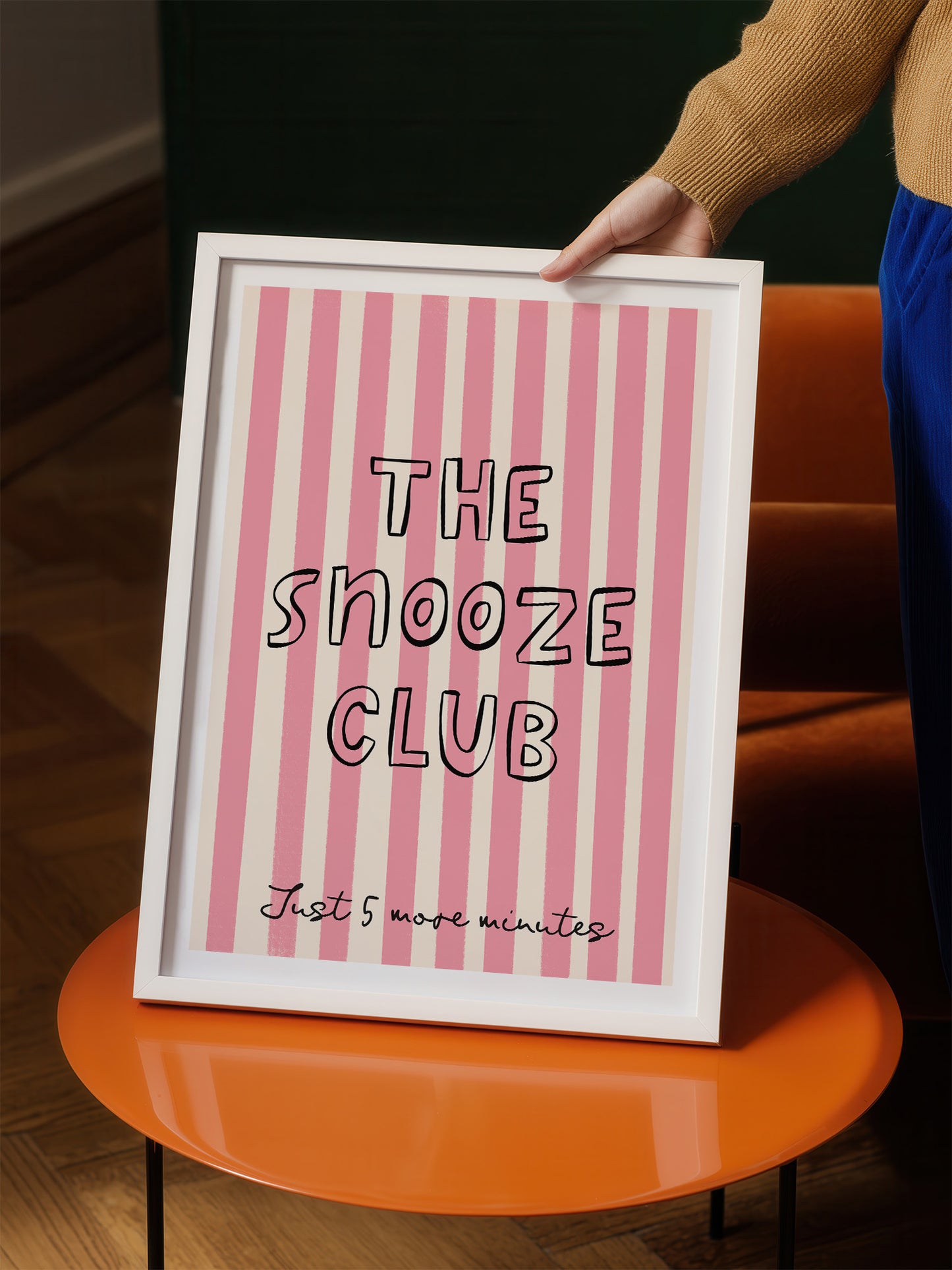 A person is holding up a framed poster with the text "THE SHOOZE CLUB" and "Just 5 more minutes" written on it.