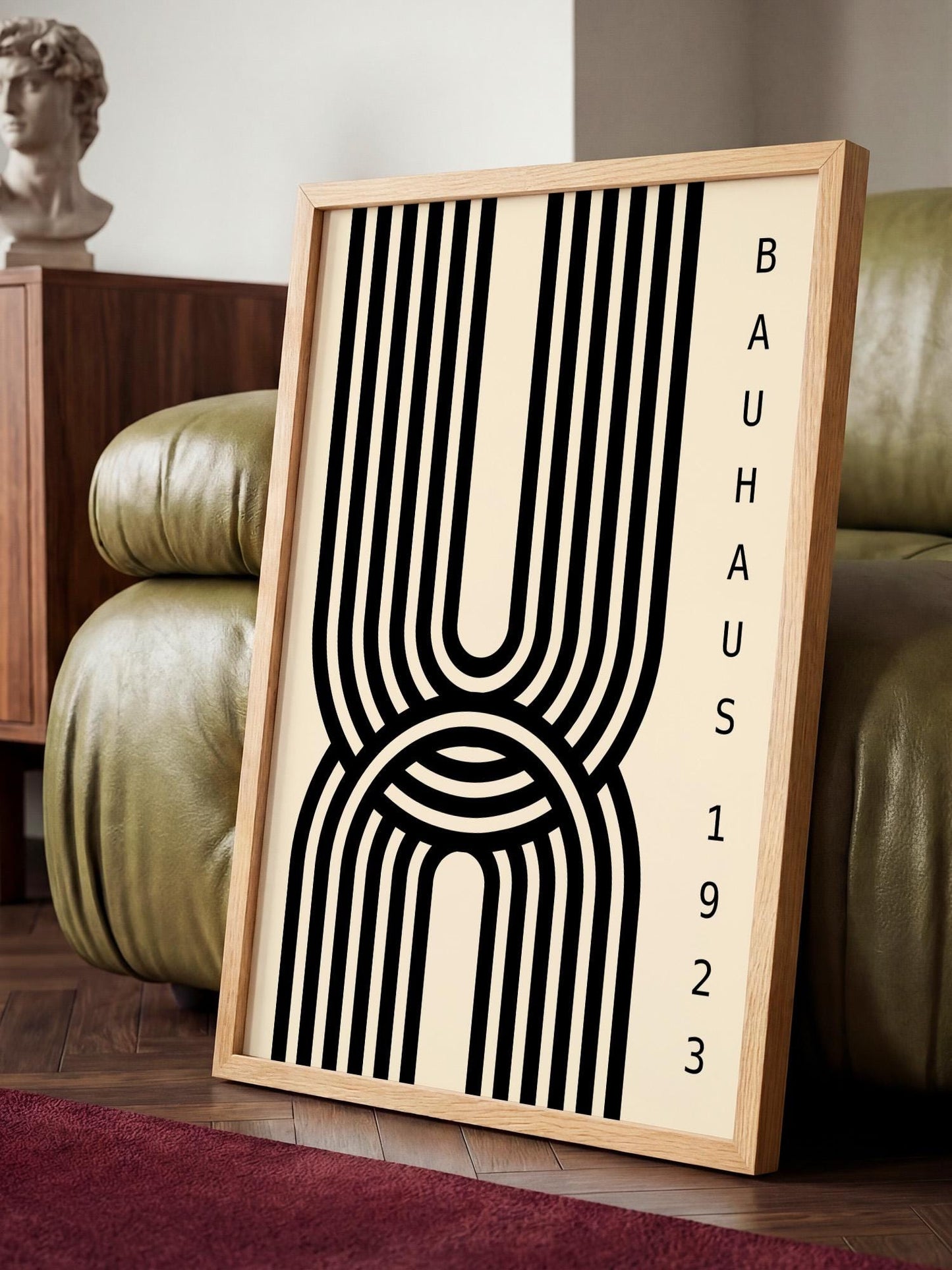 a framed poster with a striking black and white abstract design, placed on a wooden floor in a room with a green leather couch.