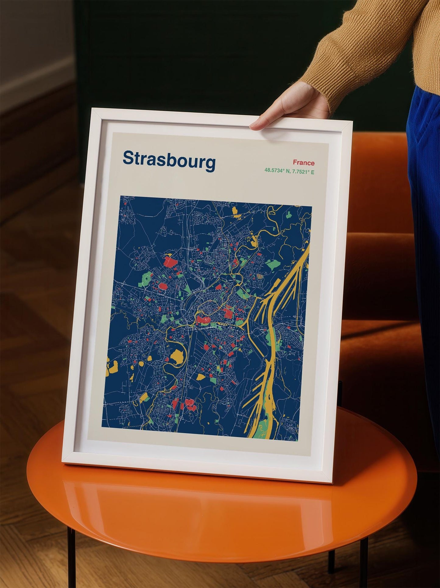 A person is holding a framed map of Strasbourg, France, which features a colorful and detailed map of the city.