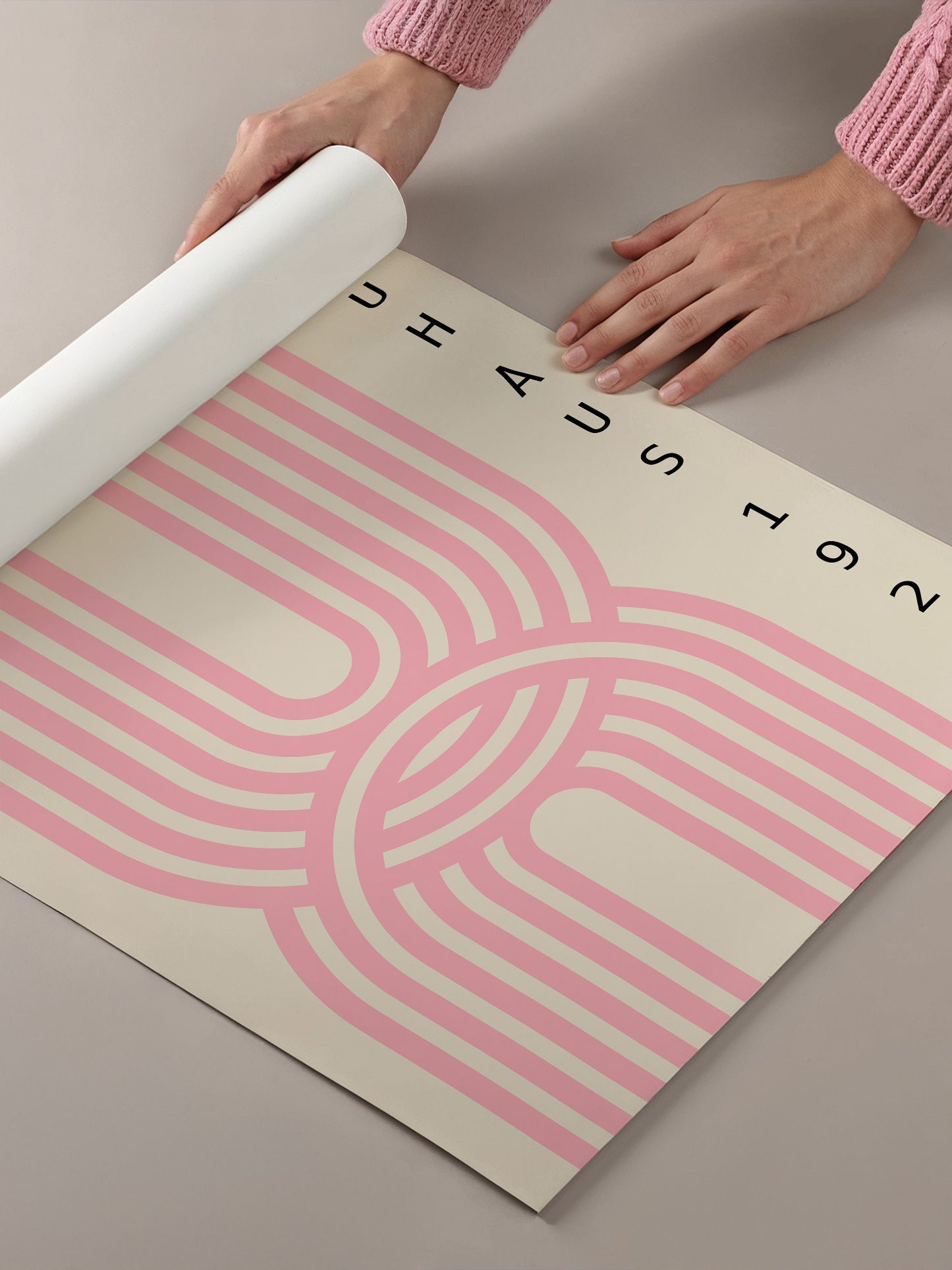 A person's hands are holding a roll of paper with a pink and white abstract design on it.