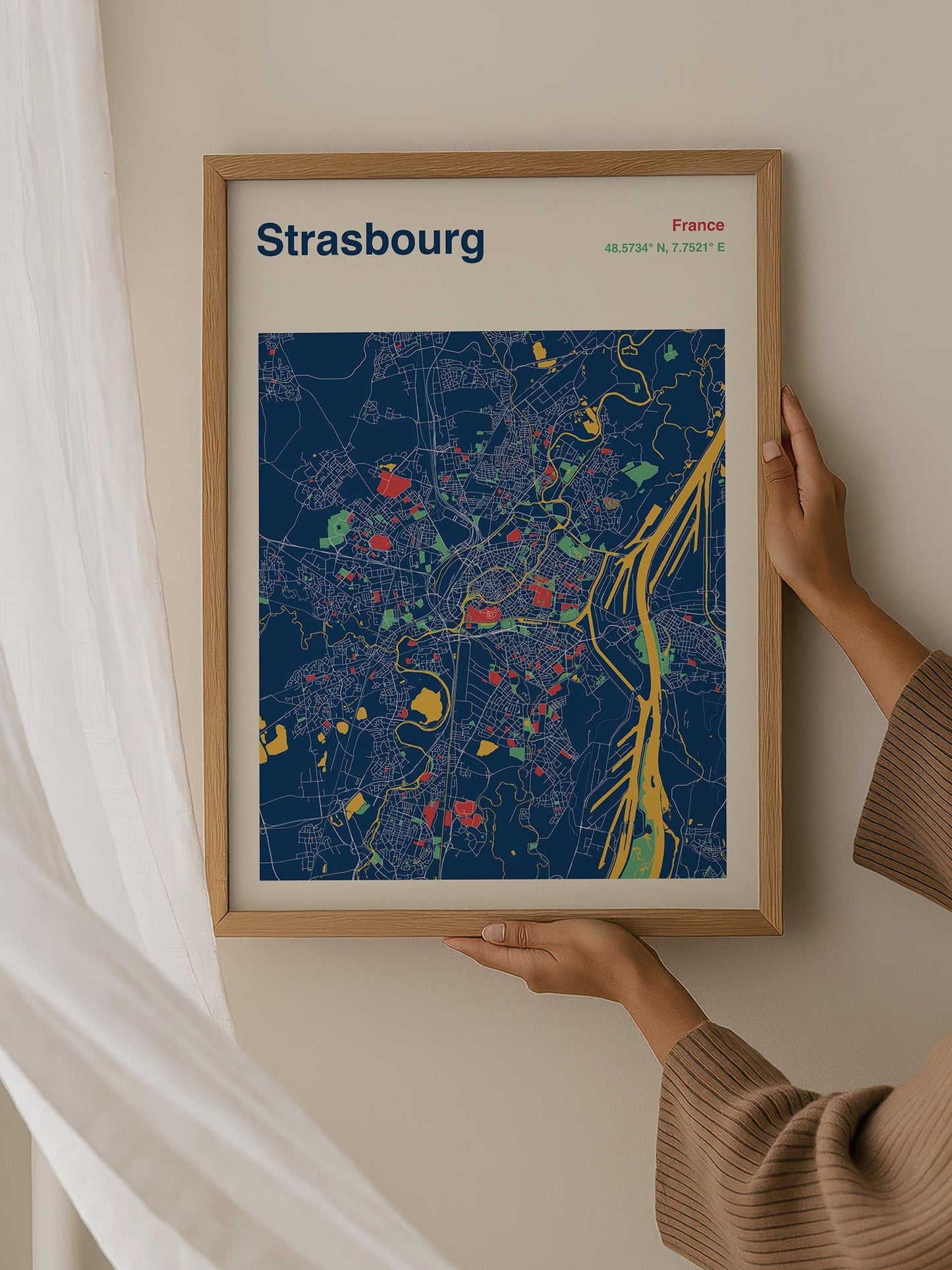 A person is holding up a framed map of Brussels, France, which displays a colorful and detailed map of the city.
