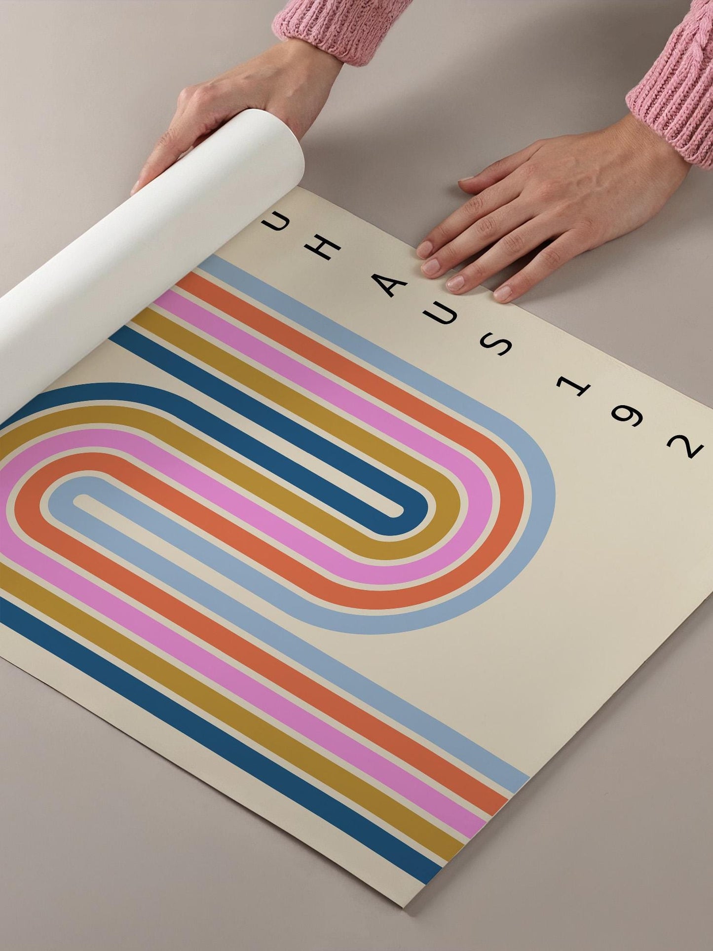 A person's hands are holding a roll of paper with a colorful abstract design featuring curved lines in various colors.