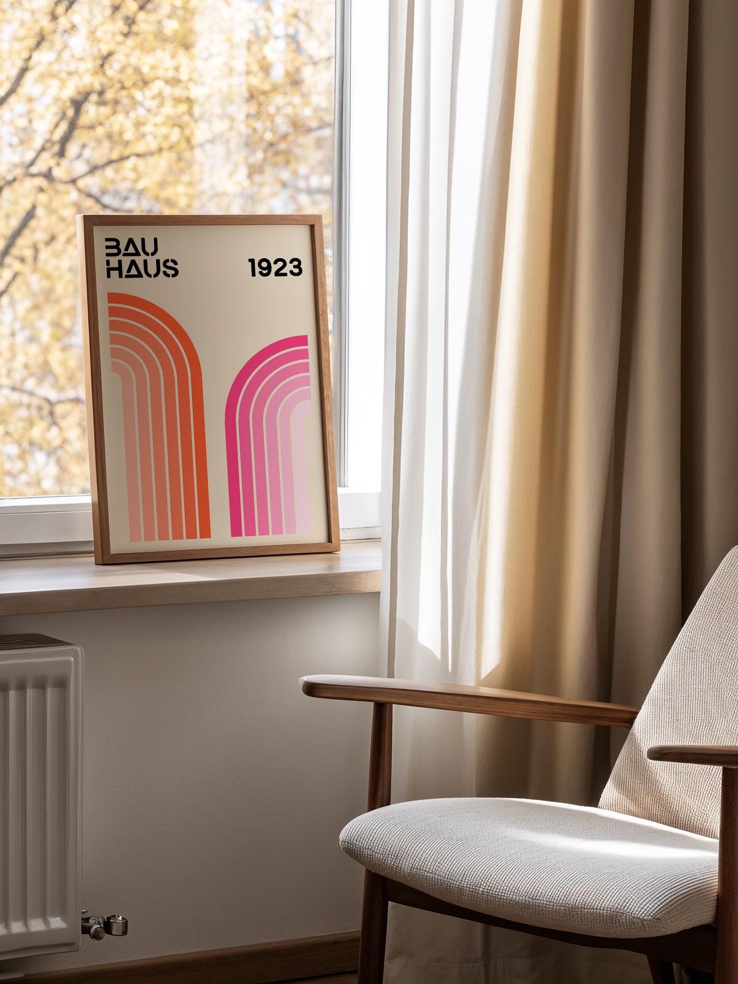a framed poster of the Bauhaus design from 1923, placed on a window sill next to a chair.