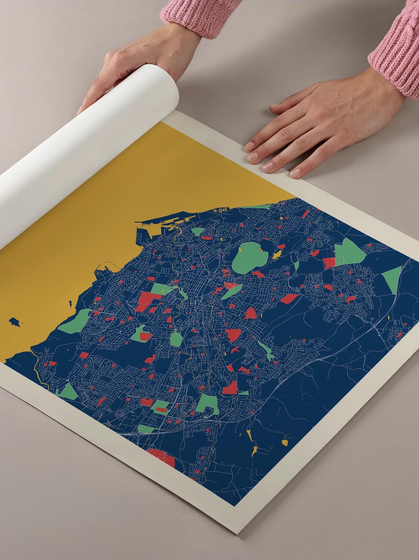 A person's hands are holding a roll of paper, which is displaying a colorful map of a city.