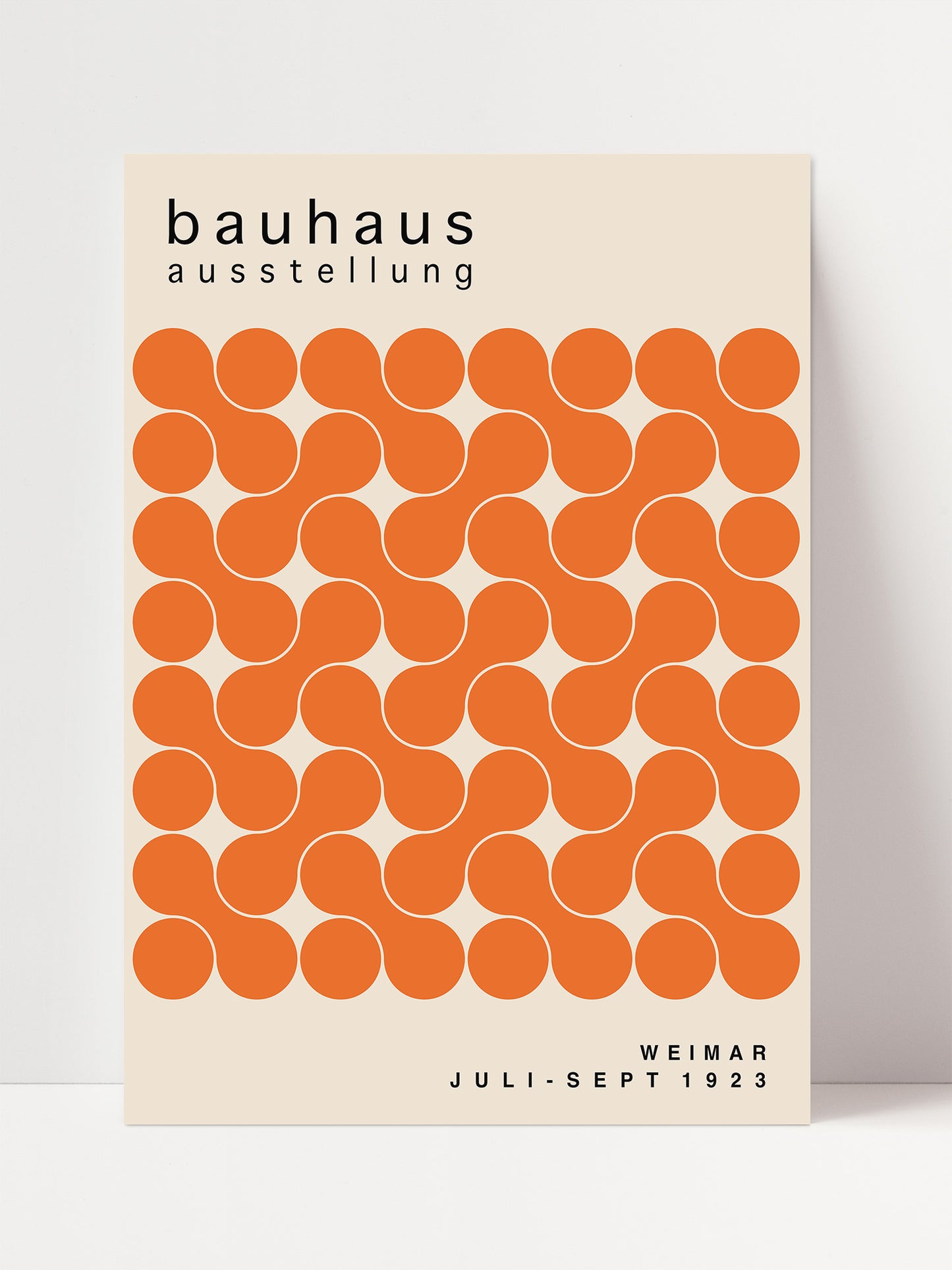 The image is a poster for the Bauhaus exhibition in Weimar, Germany, which took place from July to September 1923. The poster features a repeating pattern of orange circles on a beige background, creating a visually striking design.