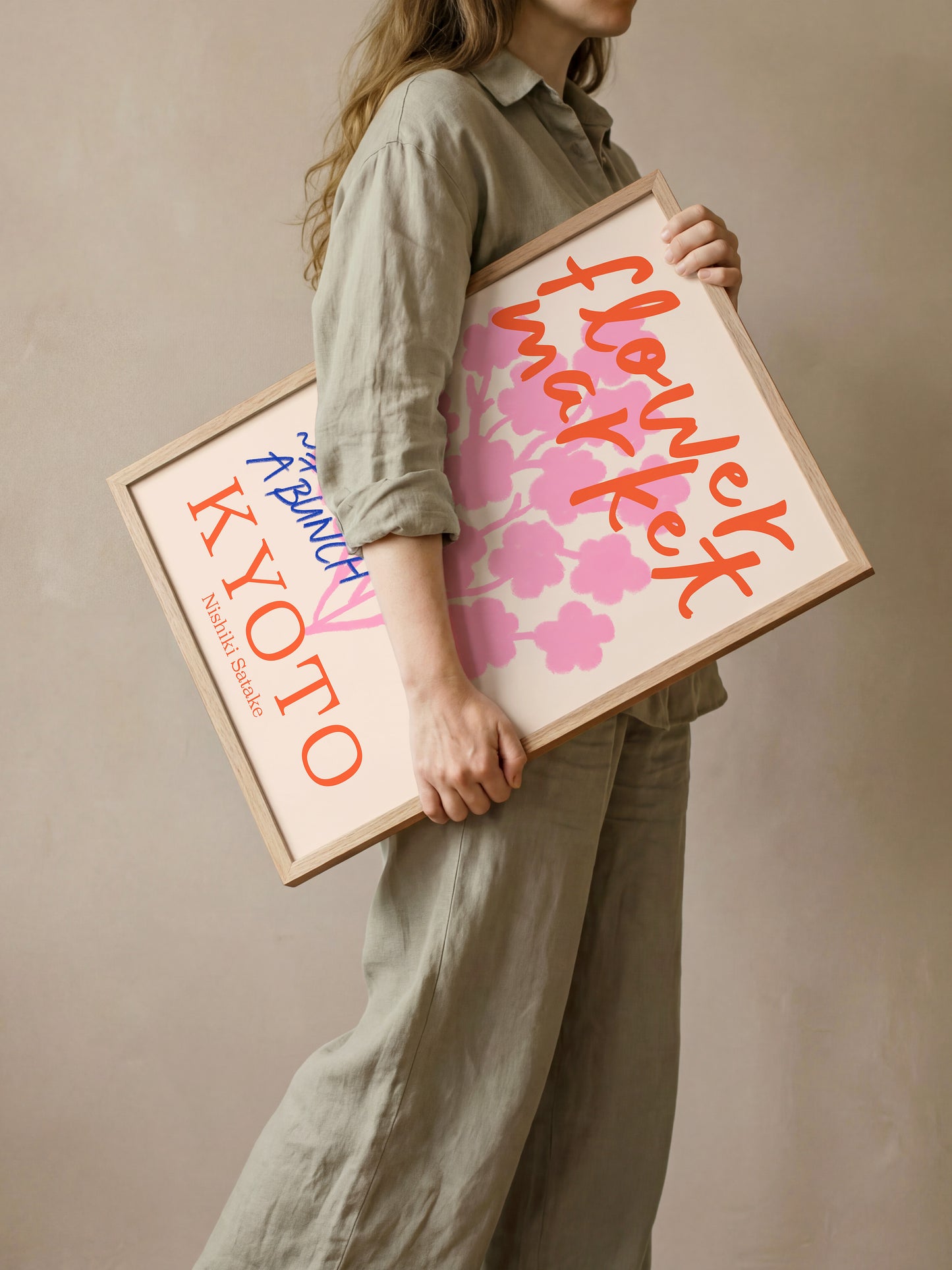 A woman is holding a framed poster with text and a floral design.
